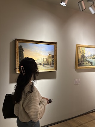 Woman viewing paintings in a museum gallery.