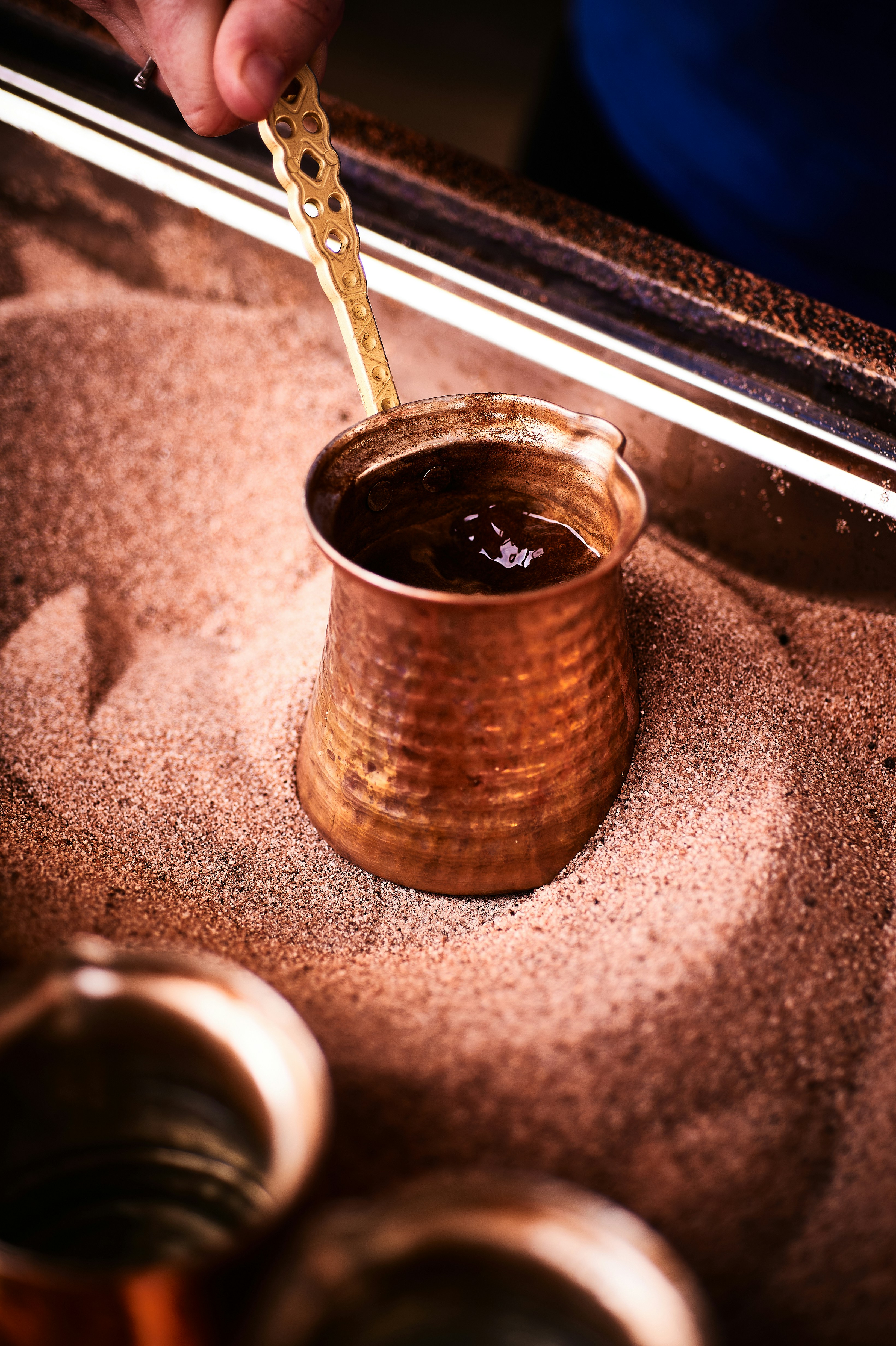 Brewing coffee in hot sand with a copper pot