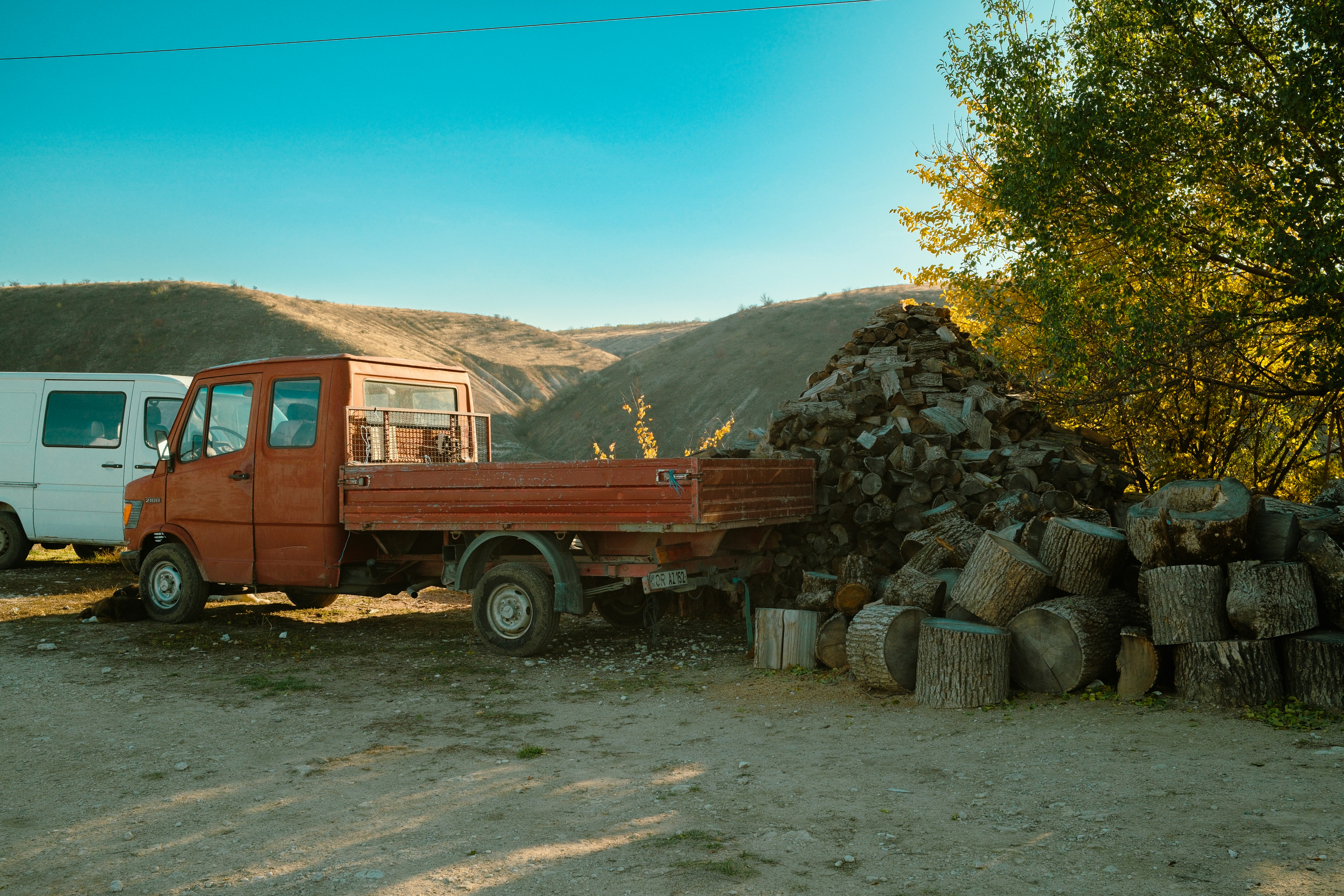 Red flatbed truck parked near stone pile