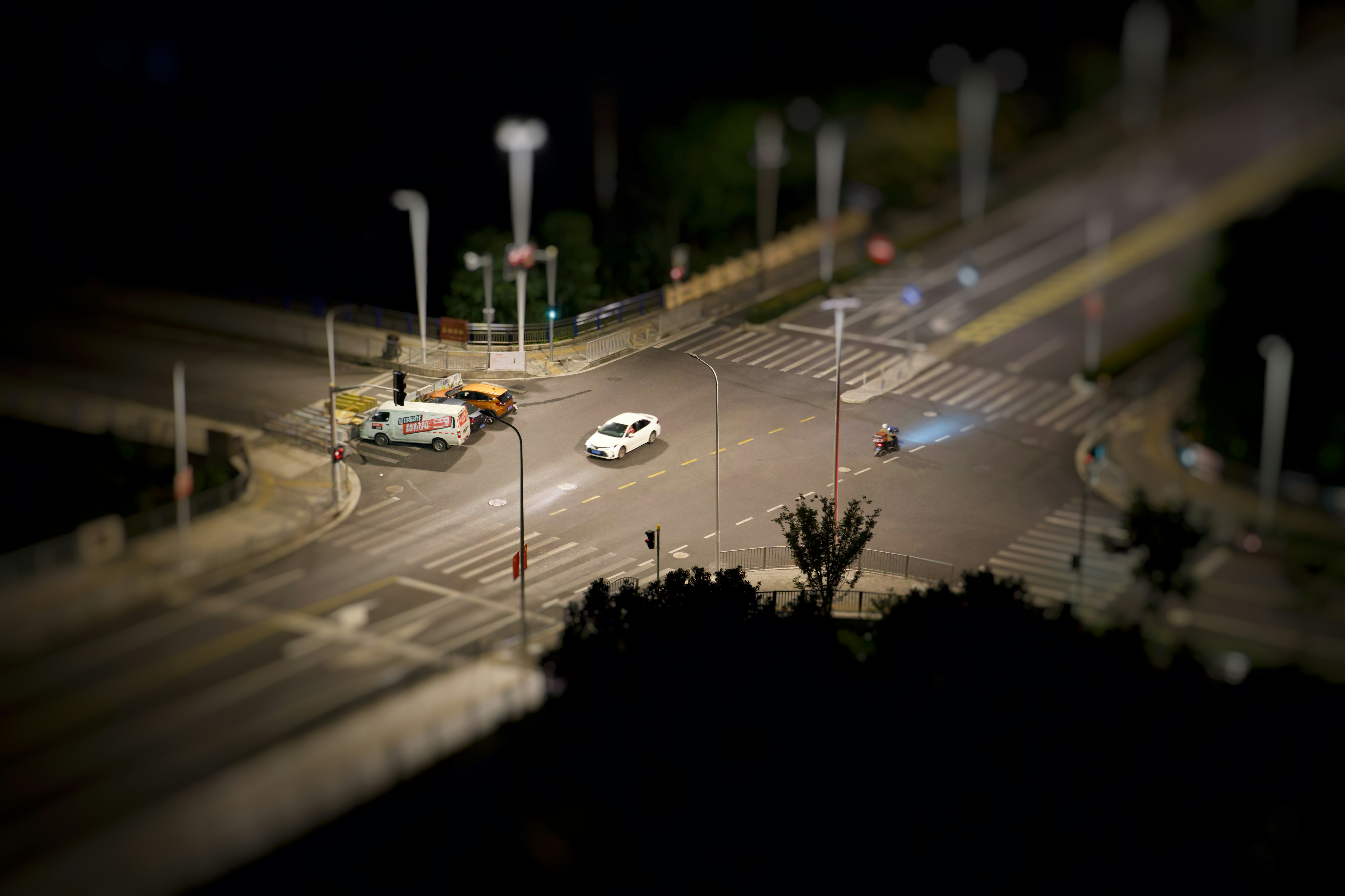 Cars driving through a city intersection at night.