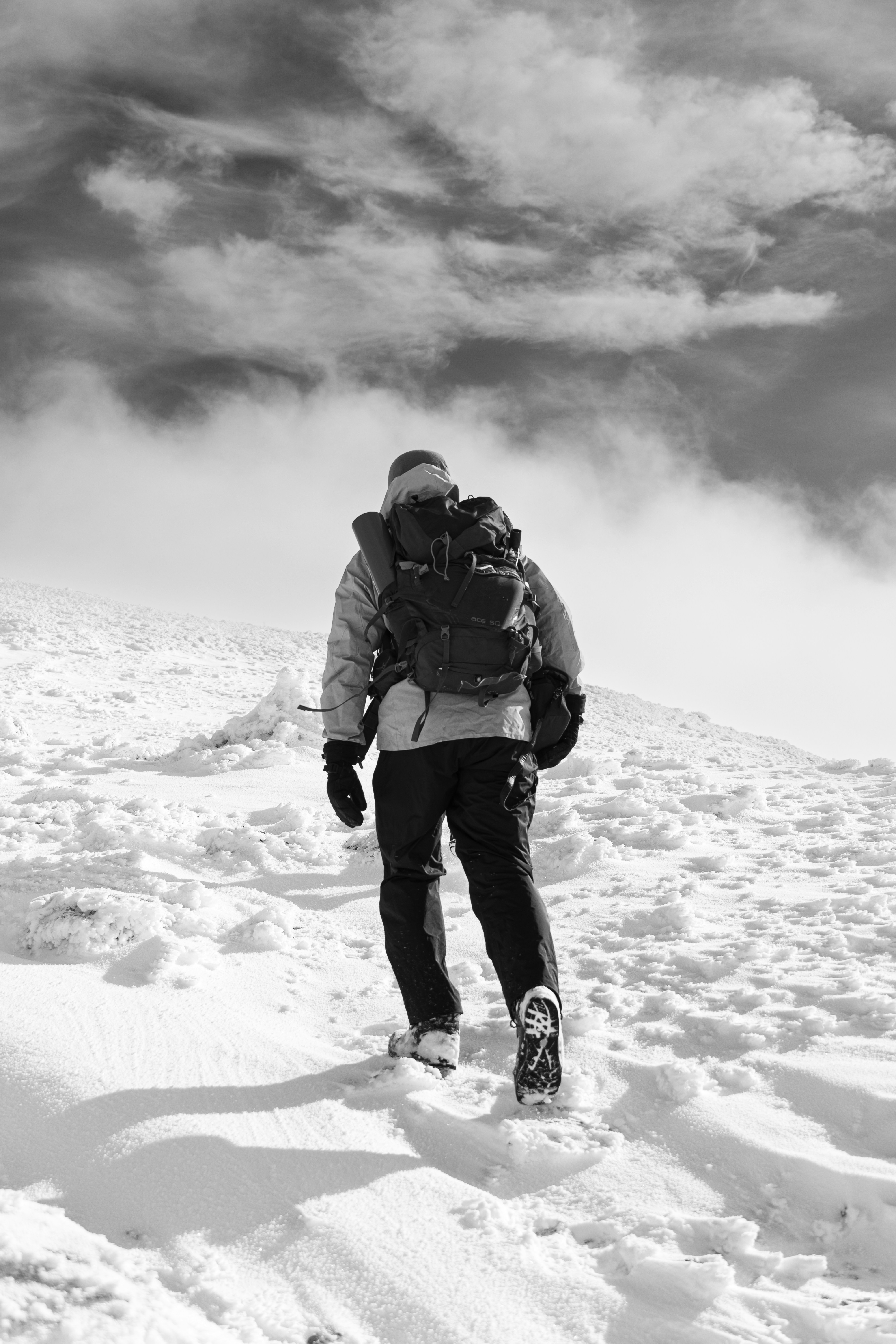 A person hikes up a snowy mountain path.