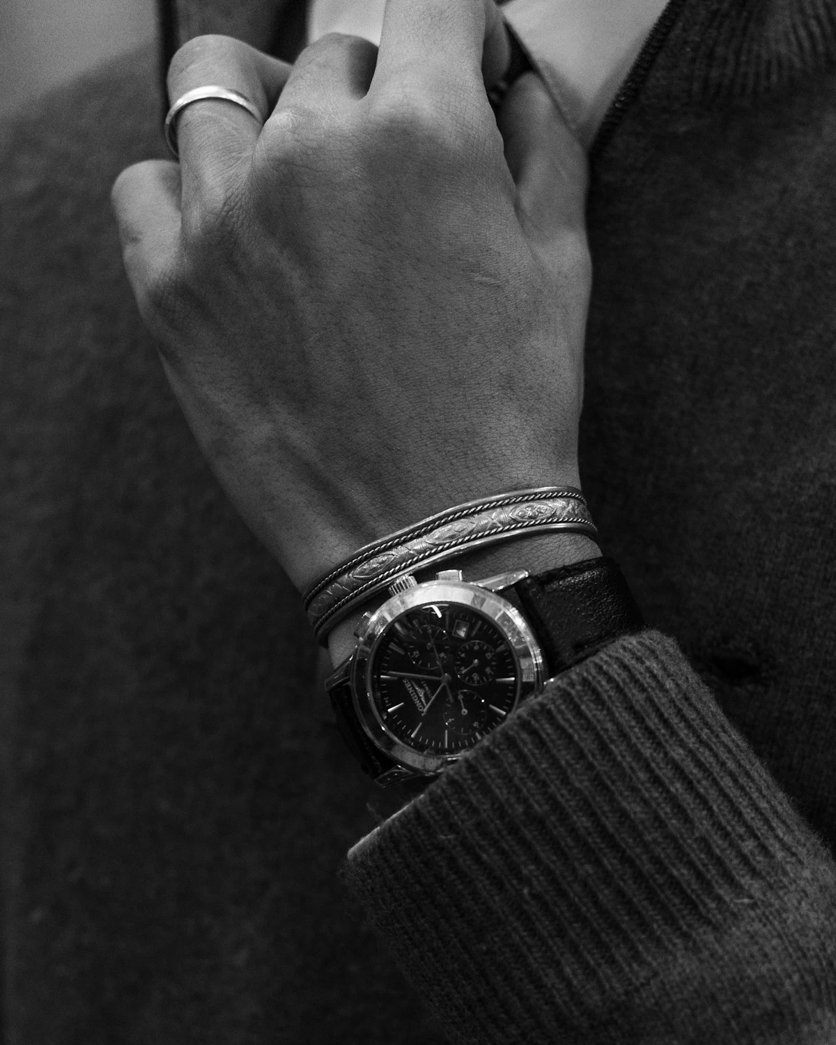 Man adjusting his tie while wearing a watch and bracelets