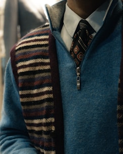 Man wearing a blue quarter-zip sweater over a collared shirt.