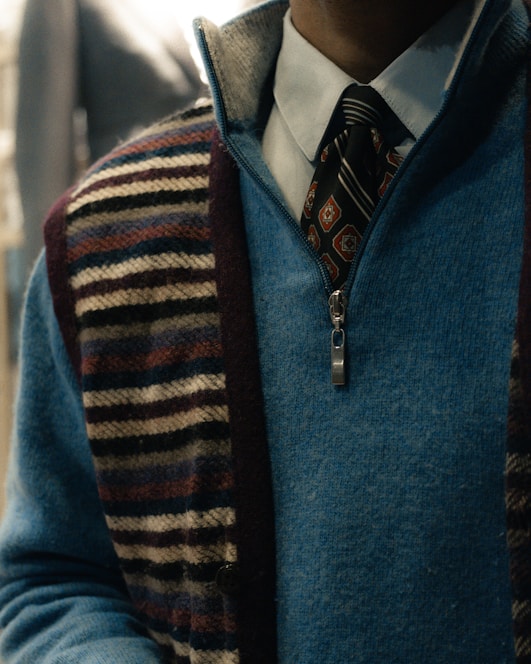 Man wearing a blue quarter-zip sweater over a collared shirt.