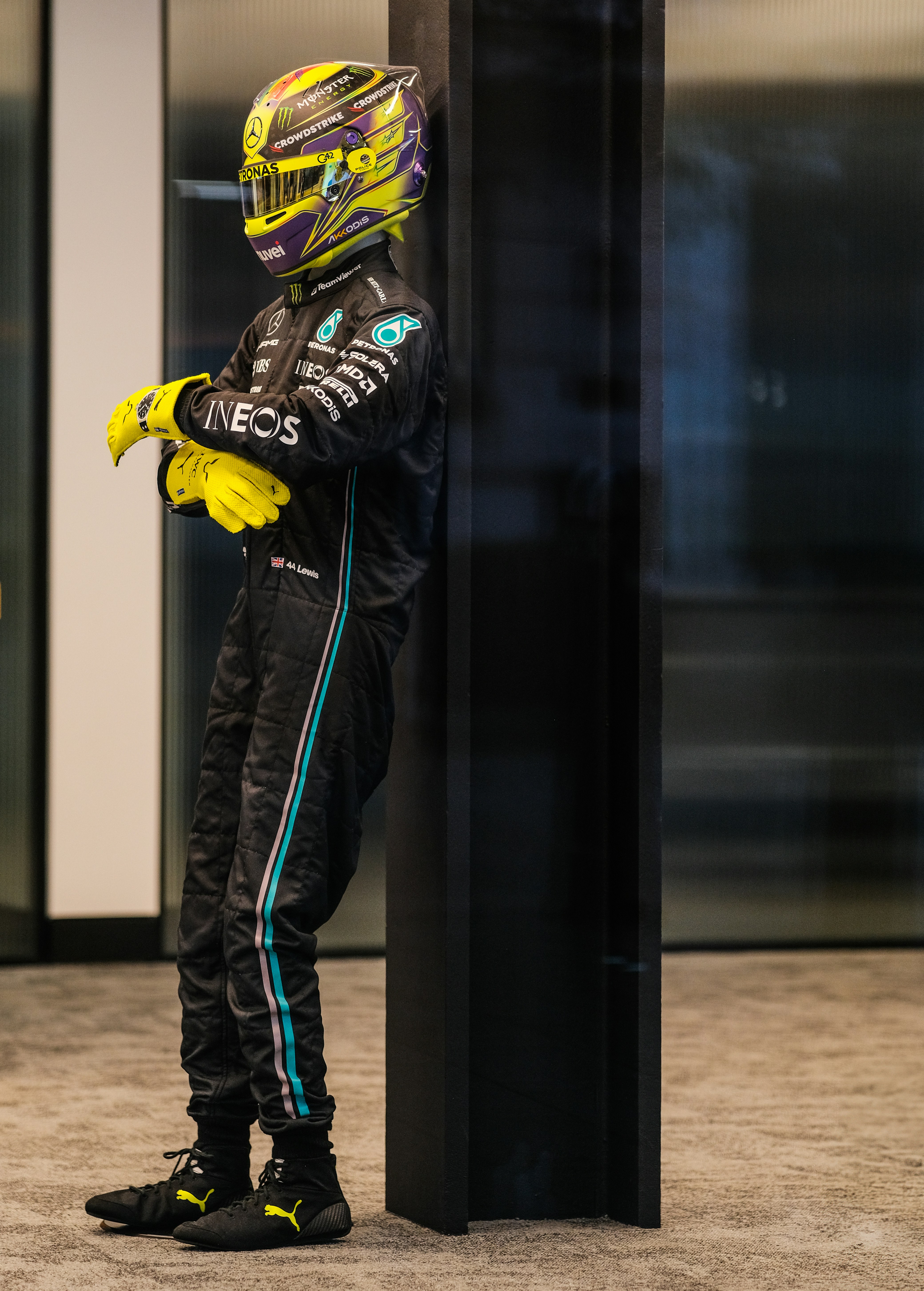 Formula 1 driver in racing suit leaning against wall