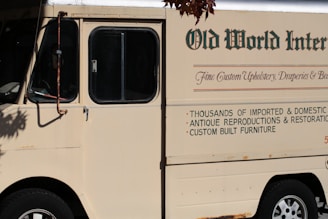 Cream colored delivery truck with text on side.