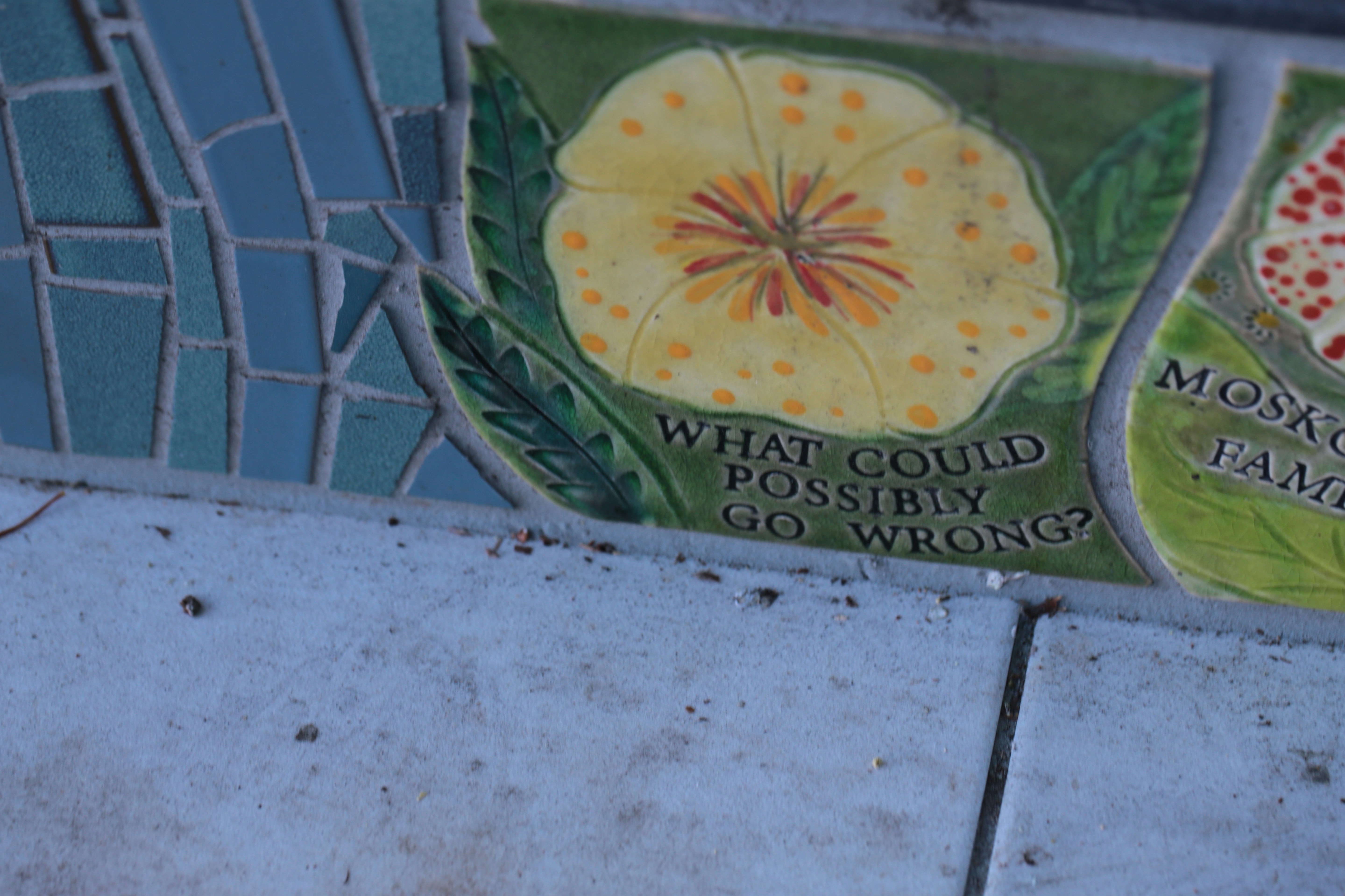 Mosaic detail with a yellow flower and text.