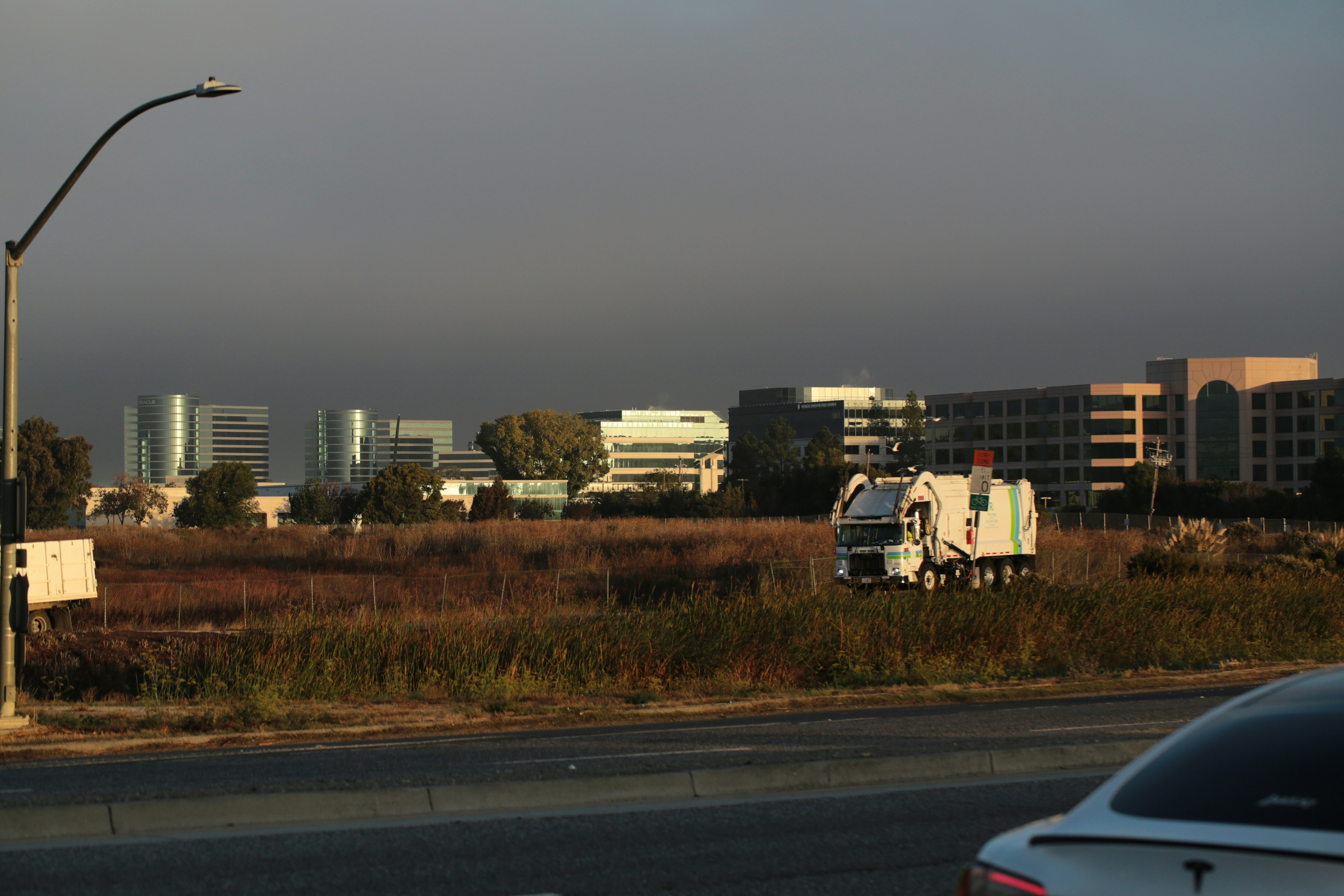 Garbage truck in a field with buildings behind