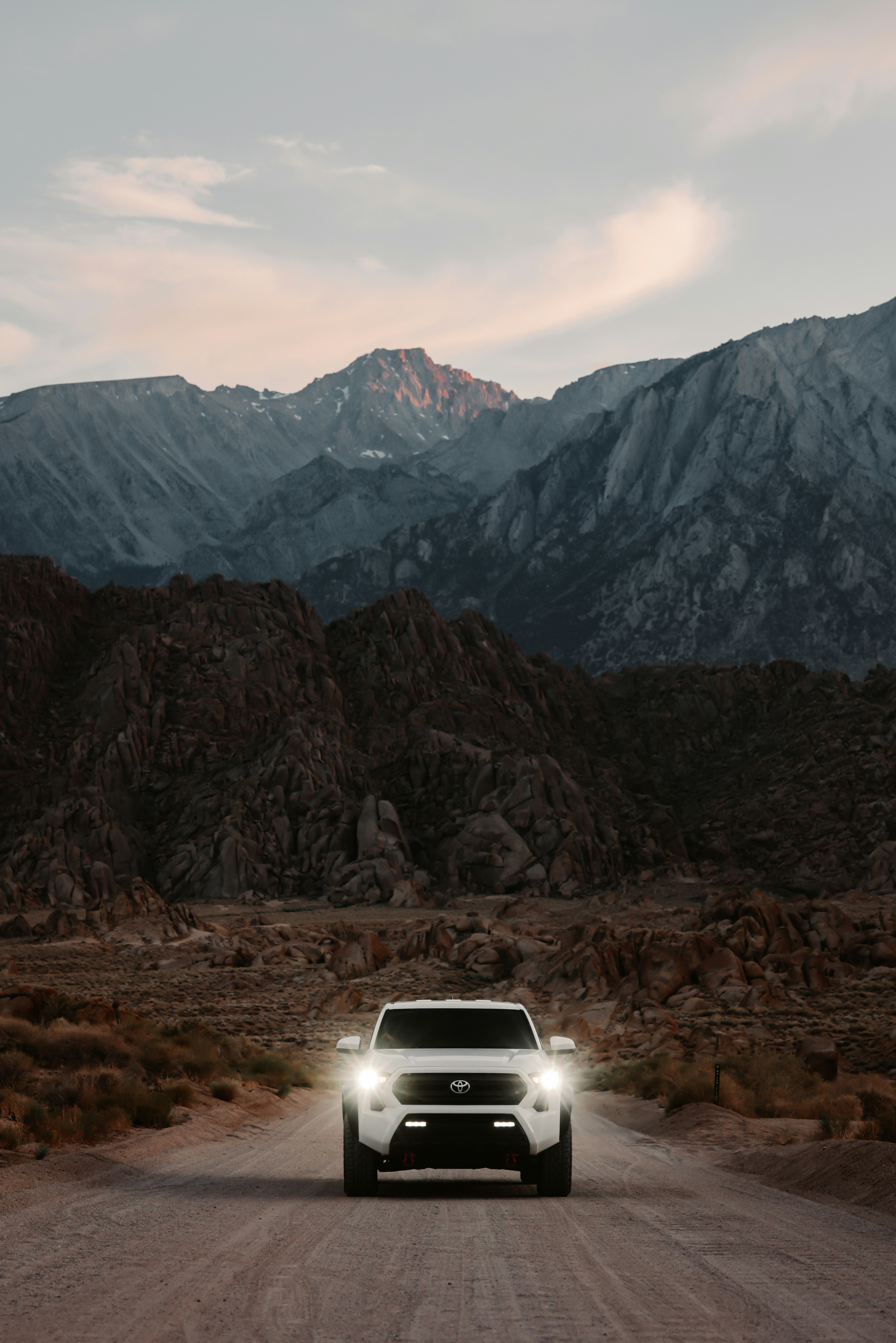 White truck driving on dirt road towards mountains