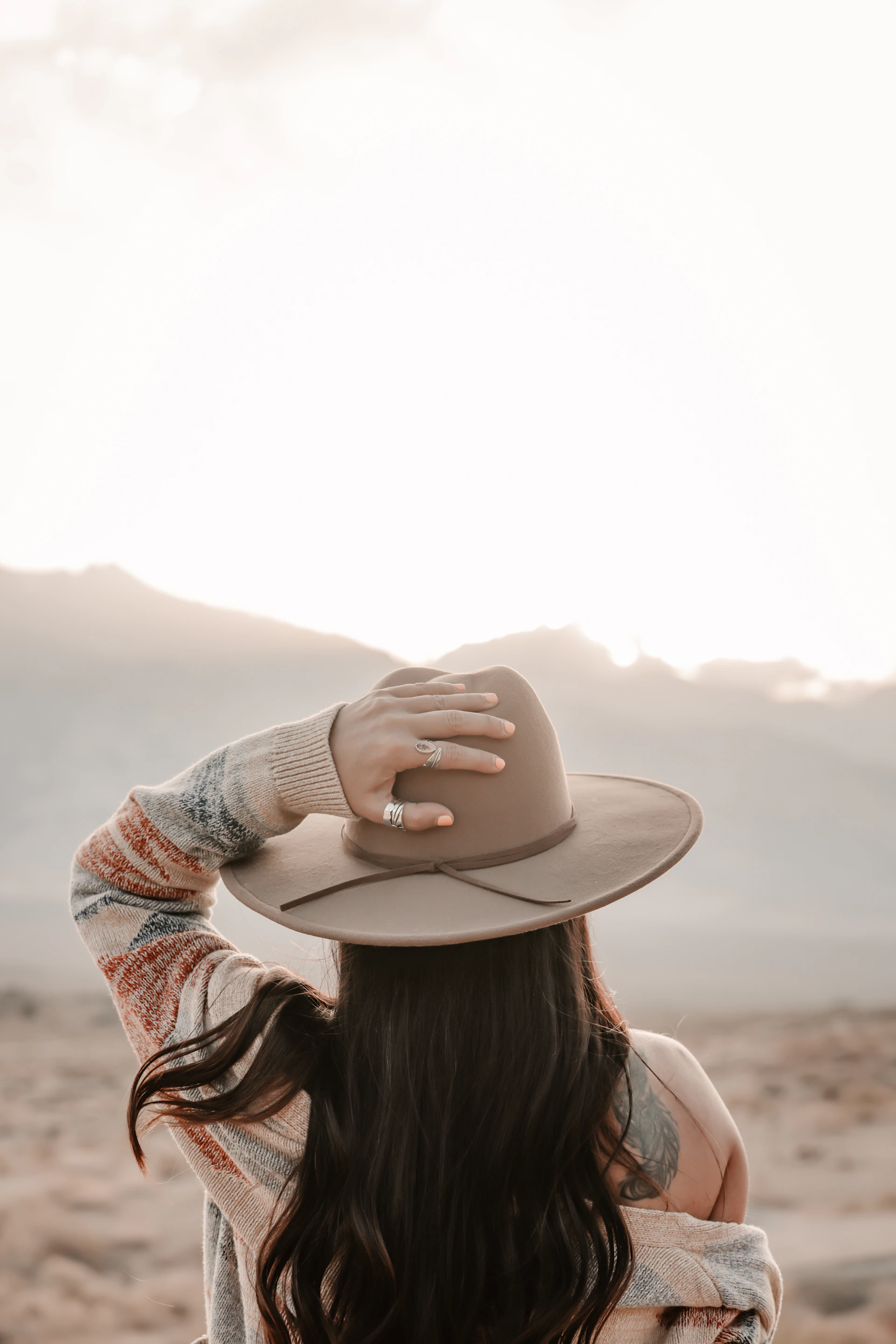Woman in hat looking at mountains at sunset
