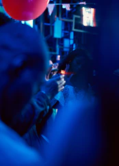 People at a dimly lit party with a red balloon.