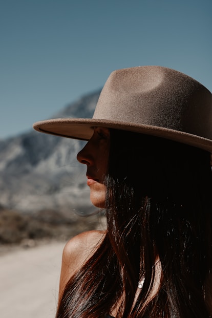 Woman wearing a wide-brimmed hat with mountains behind her