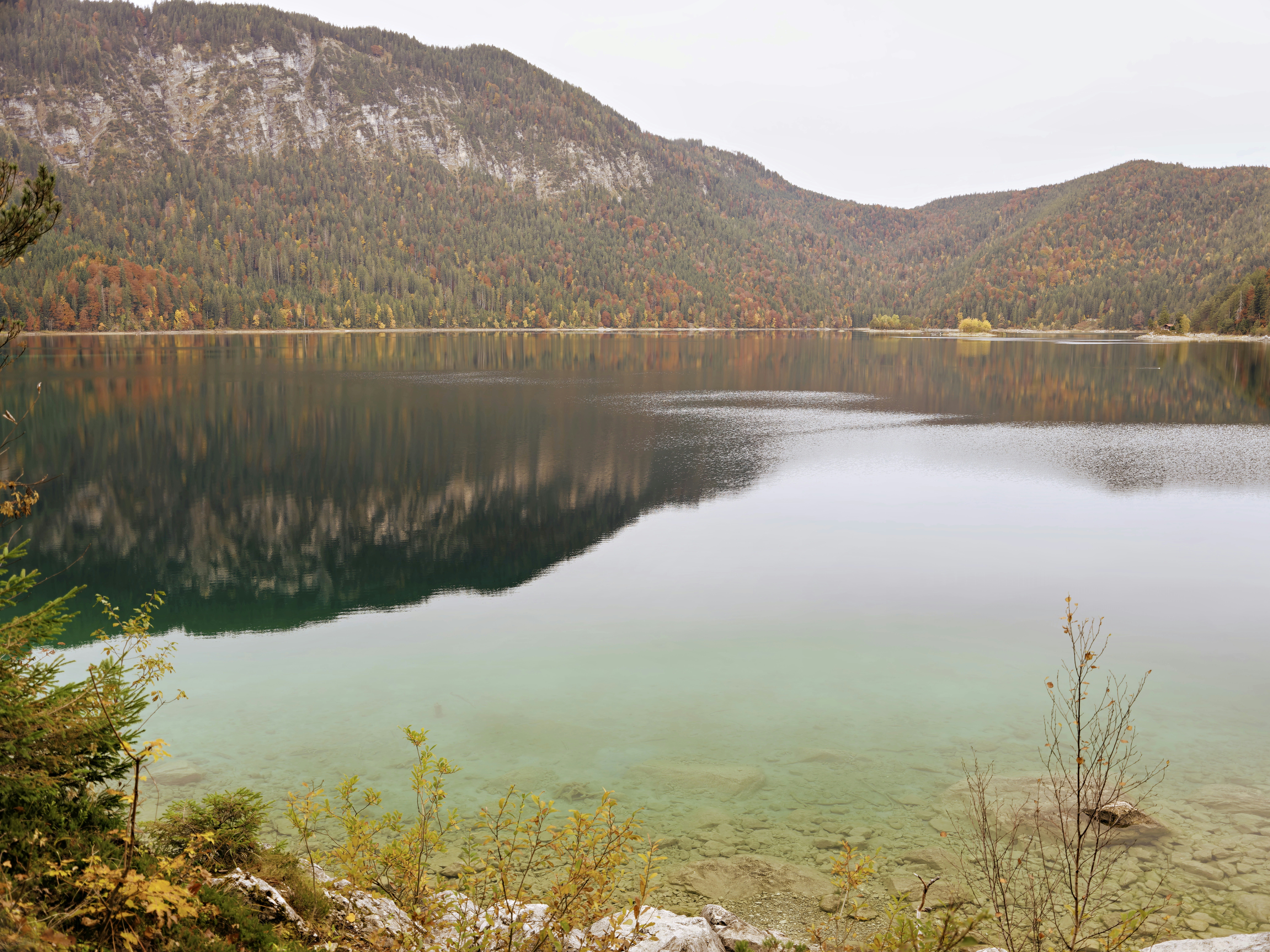 Calm lake reflecting mountains and autumn trees