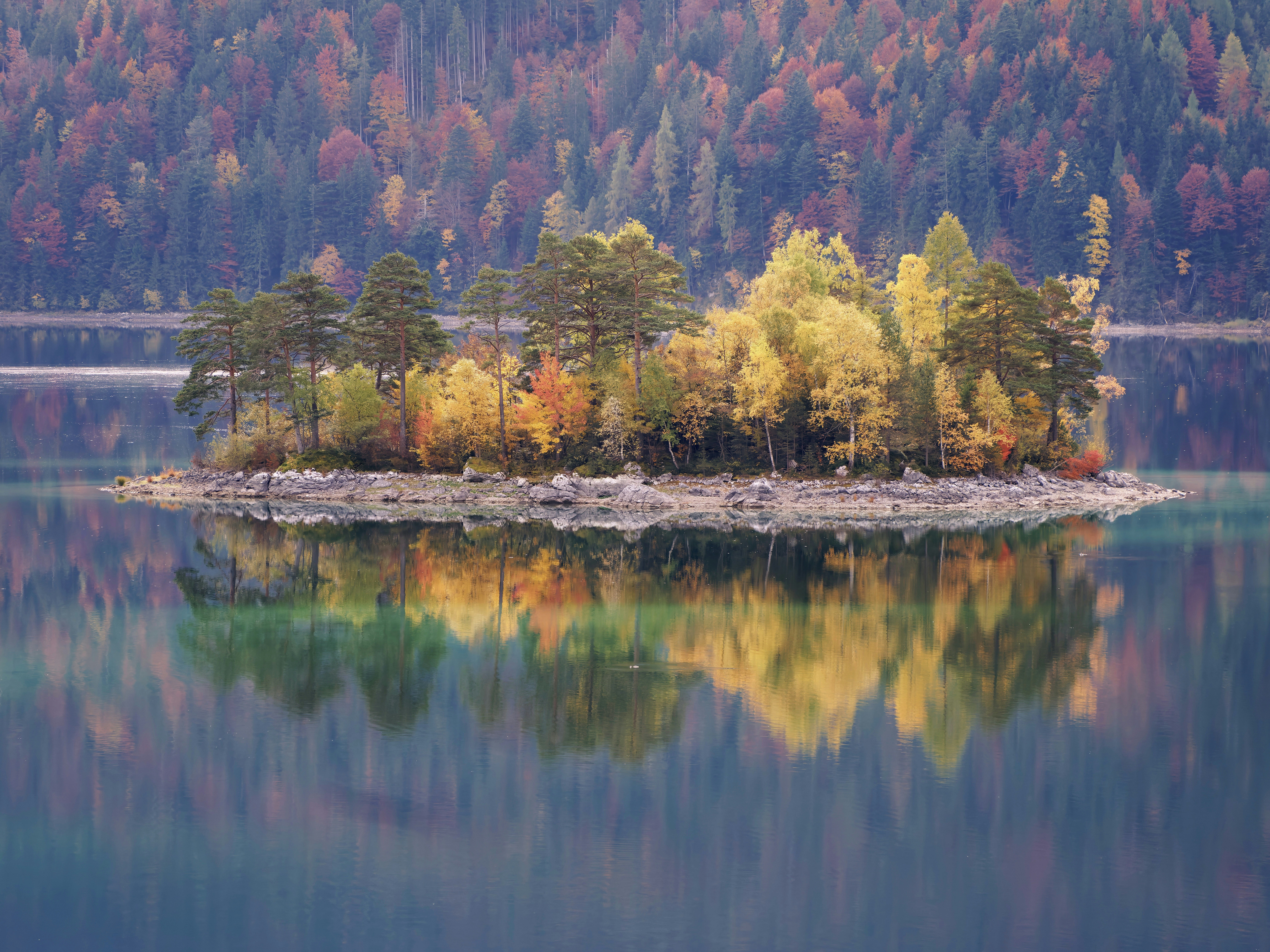 Autumn island with colorful trees reflected in lake