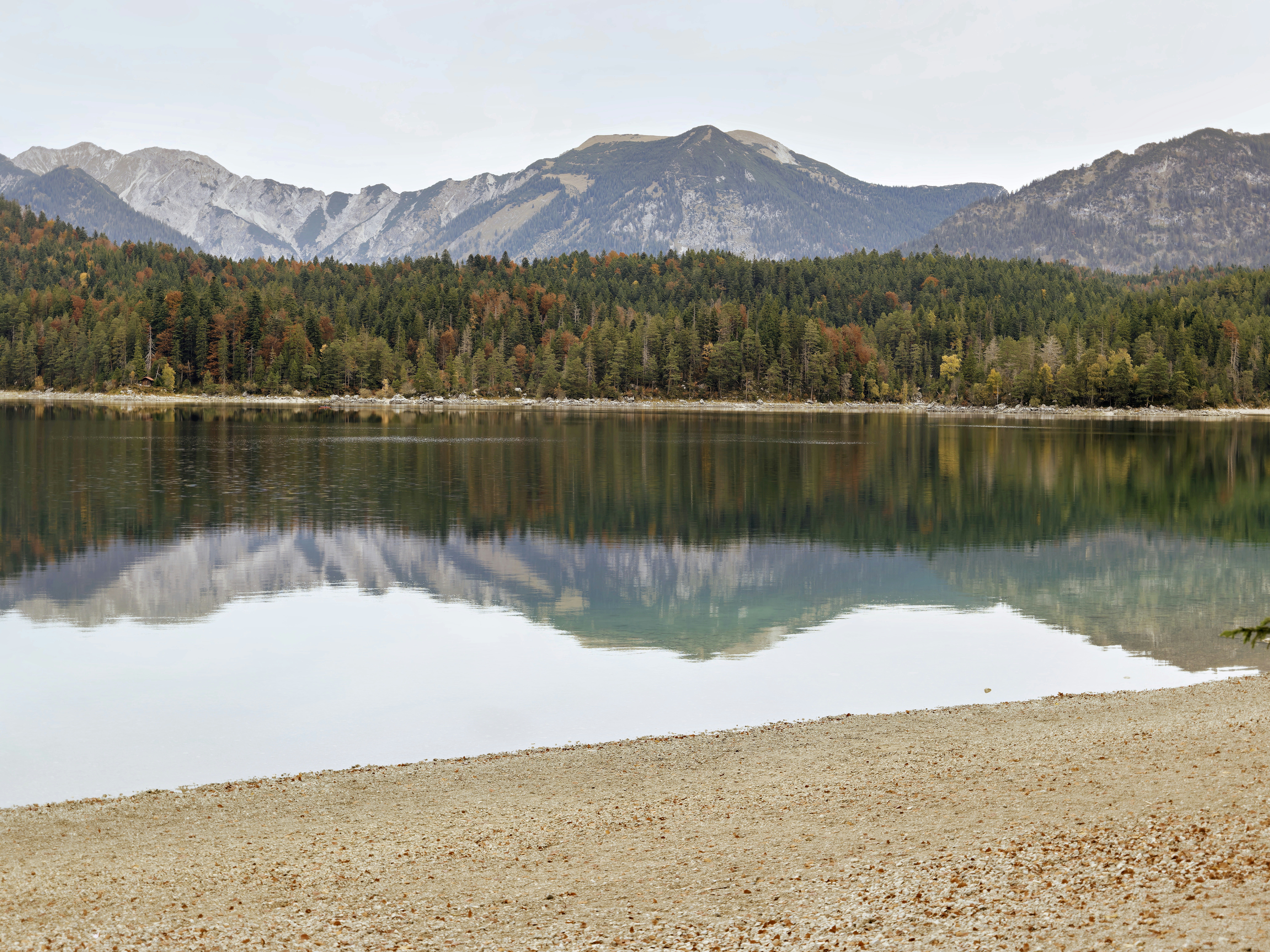 Calm lake reflecting mountains and trees under a clear sky