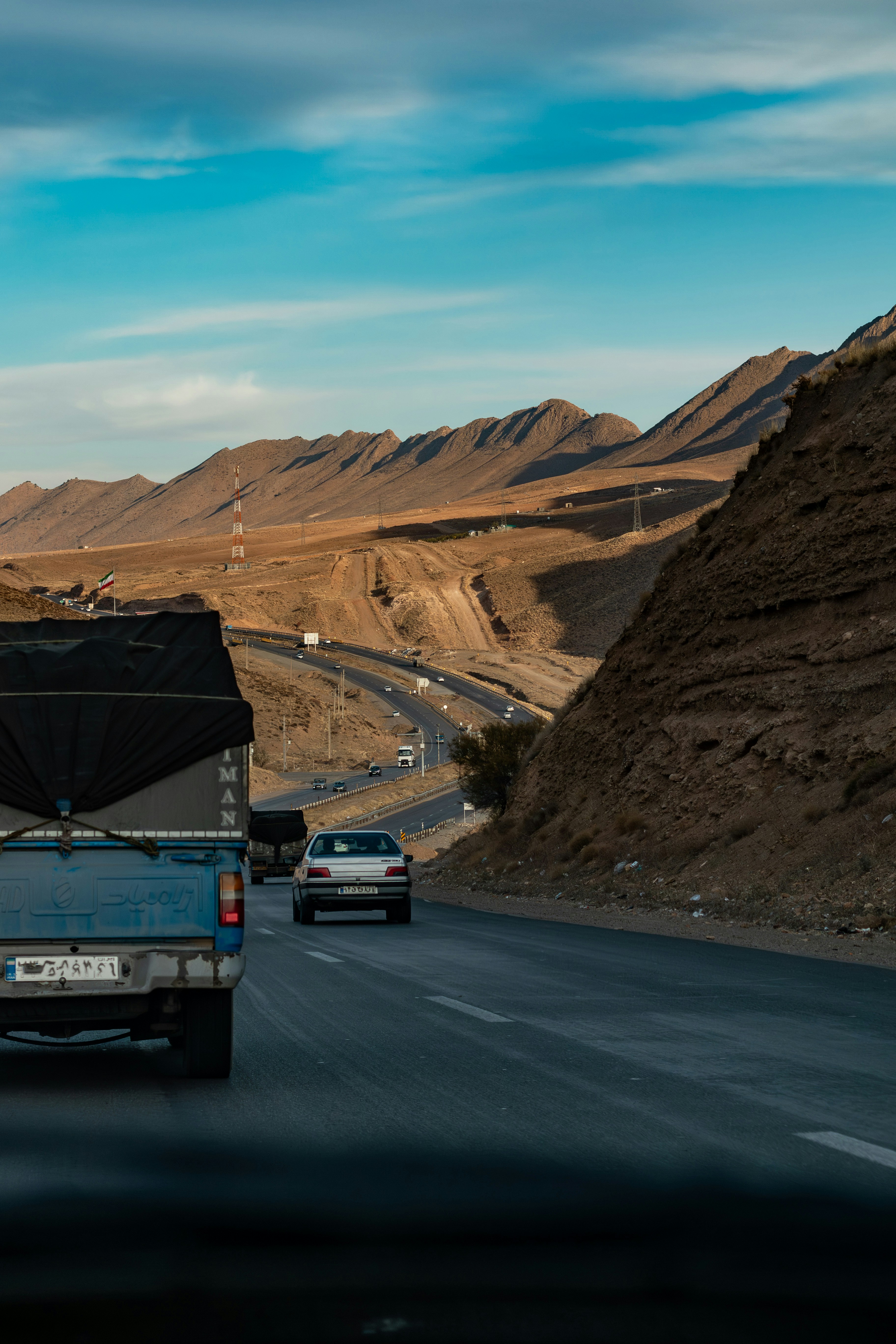 Des voitures sur une autoroute serpentant à travers des montagnes arides.
