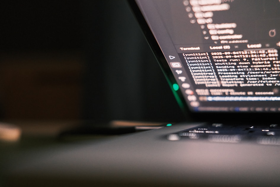 Layar laptop yang menampilkan baris kode program di lingkungan gelap