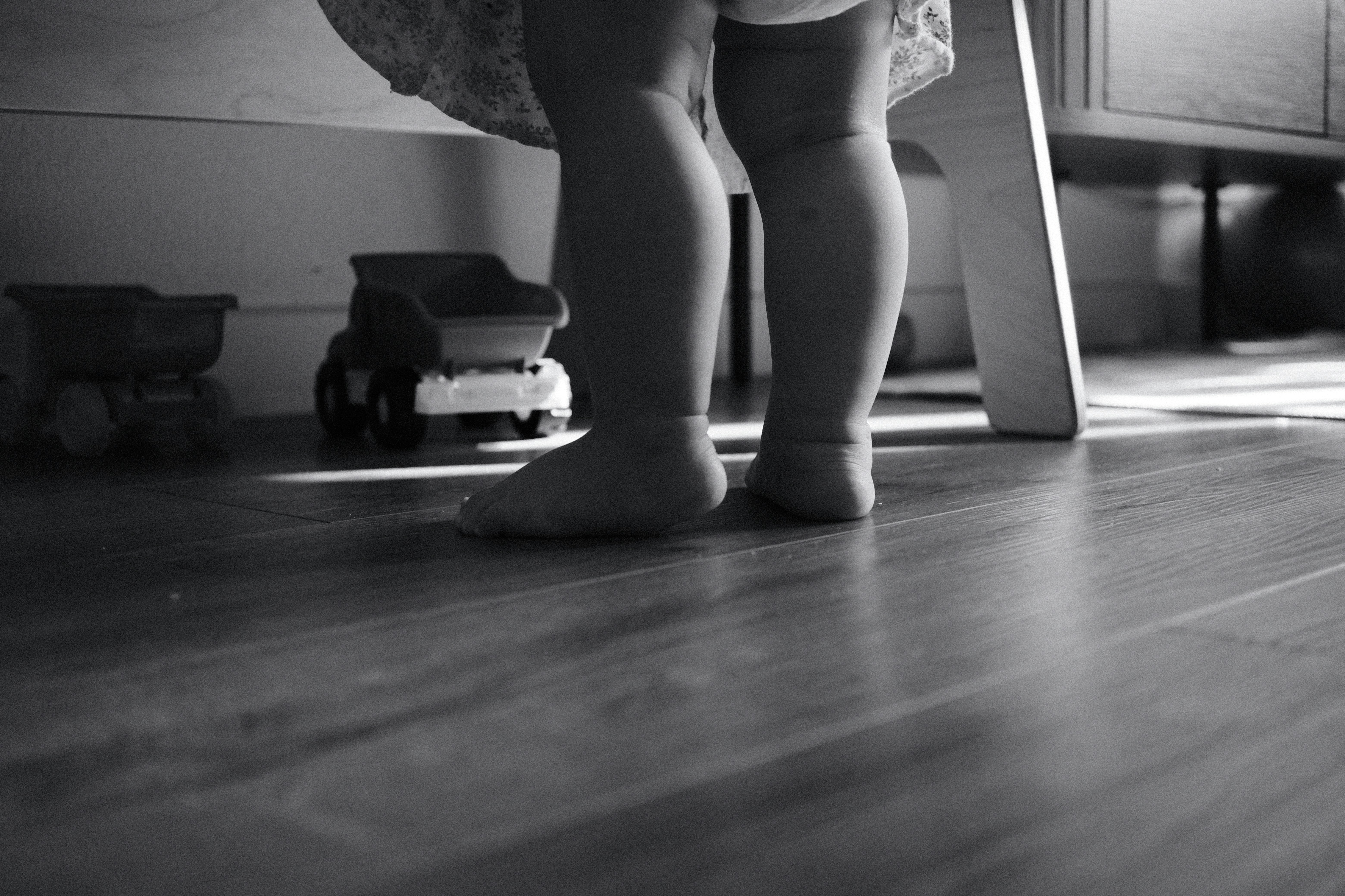 Bare feet of a child standing on a wooden floor.