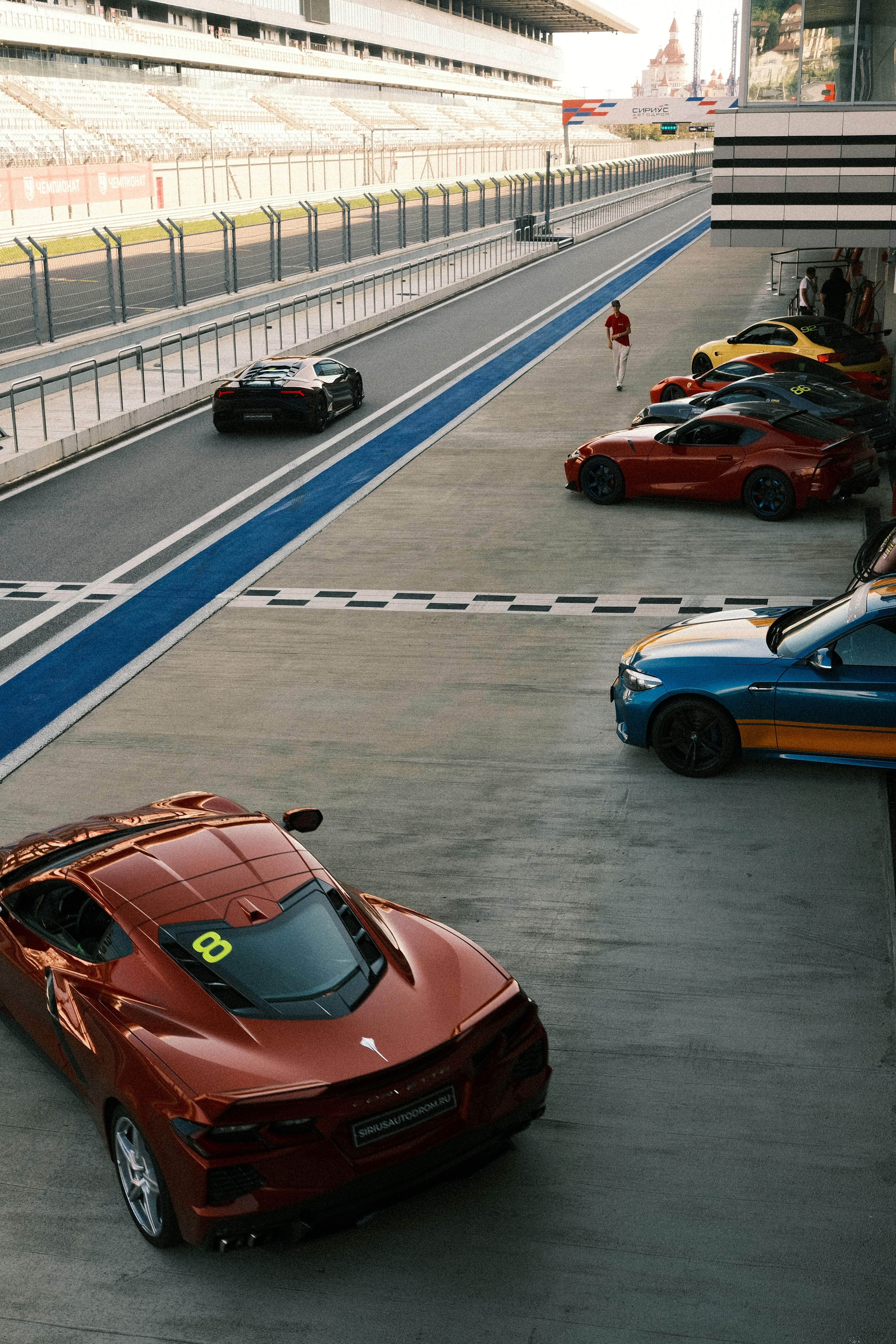 Sports cars lined up on a race track pit lane.