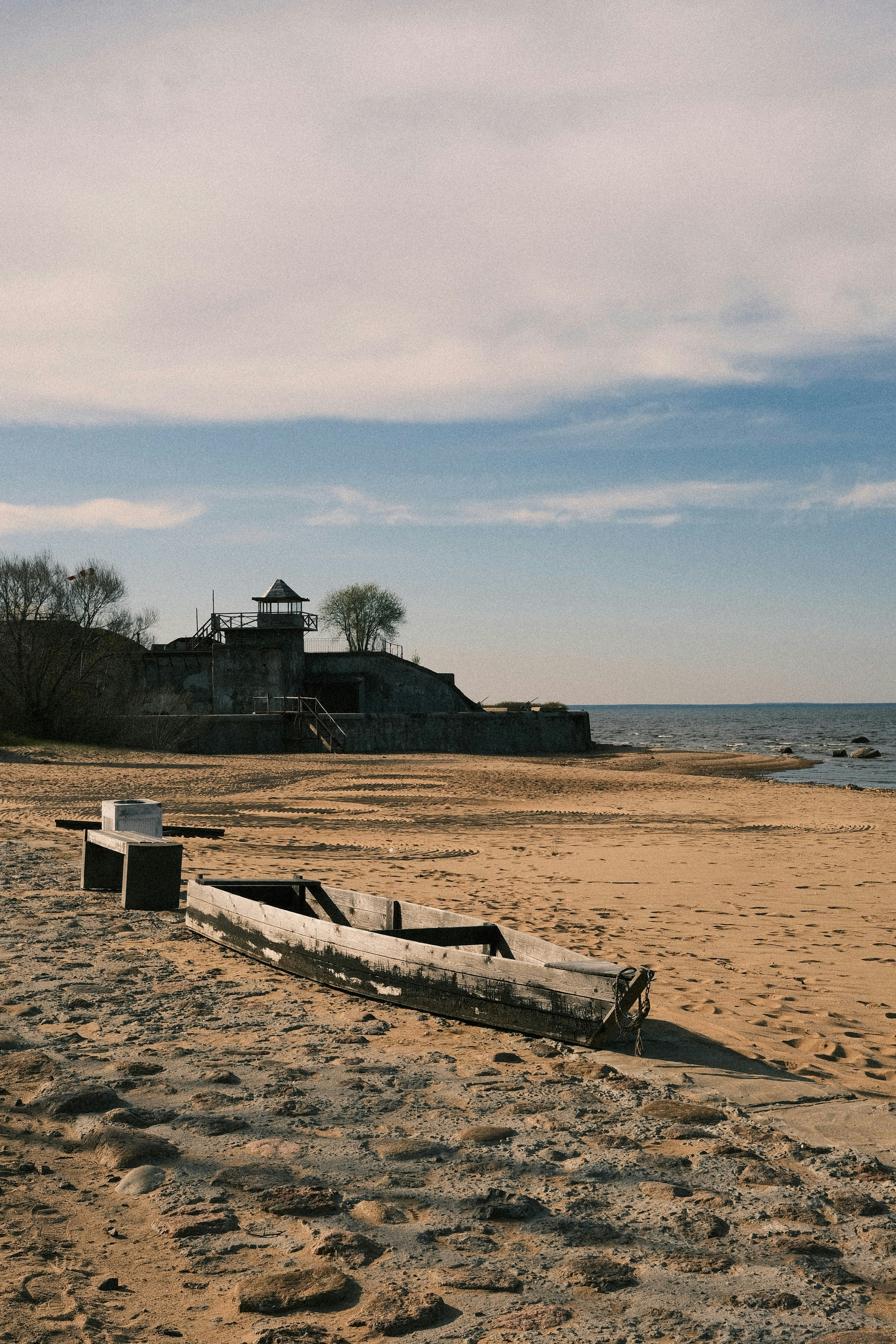Old wooden boat on a sandy beach near ruins.