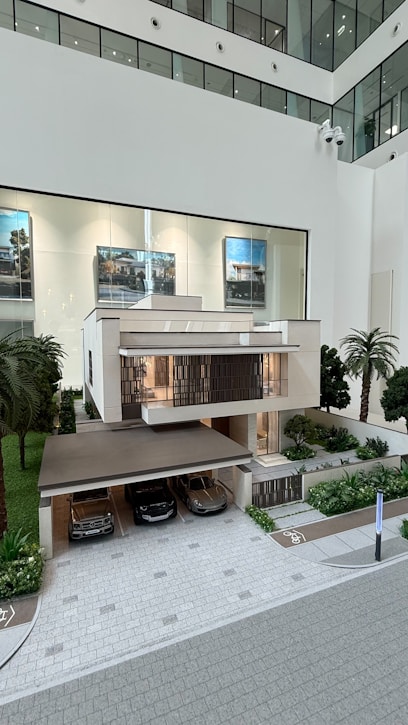 Modern house model with cars in driveway and outside garage.