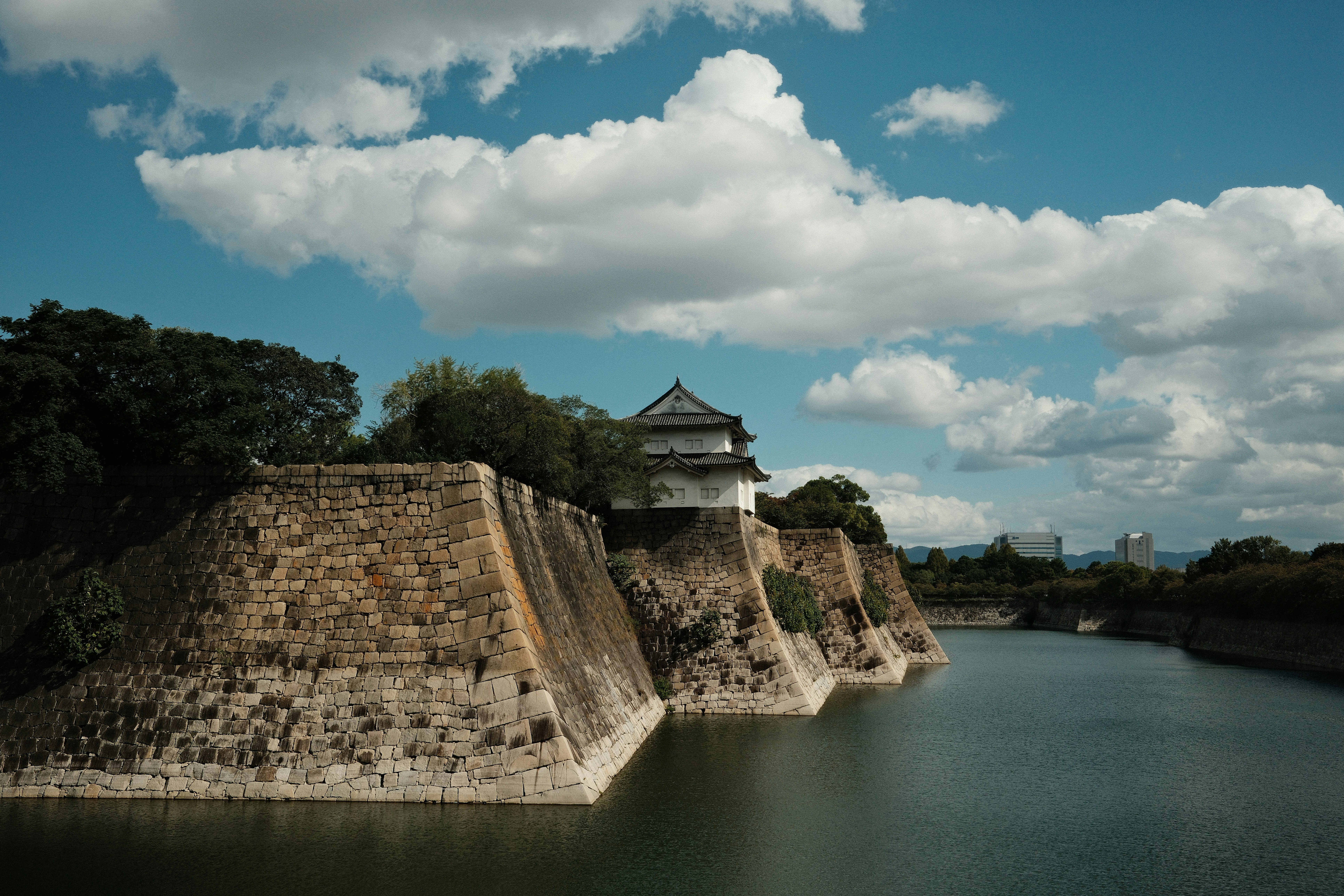 Castle walls and moat under a cloudy blue sky