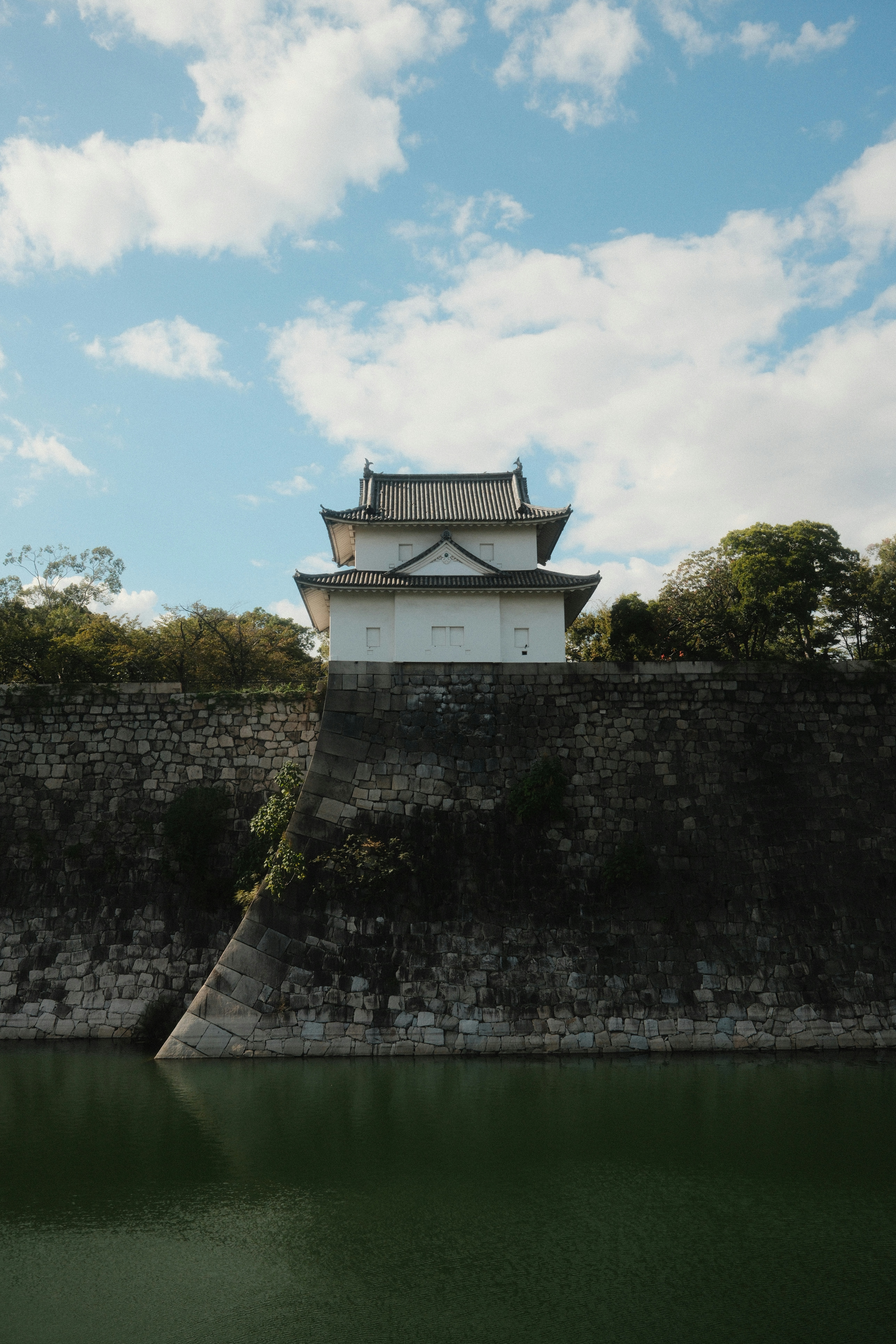 White japanese castle structure on stone wall above water