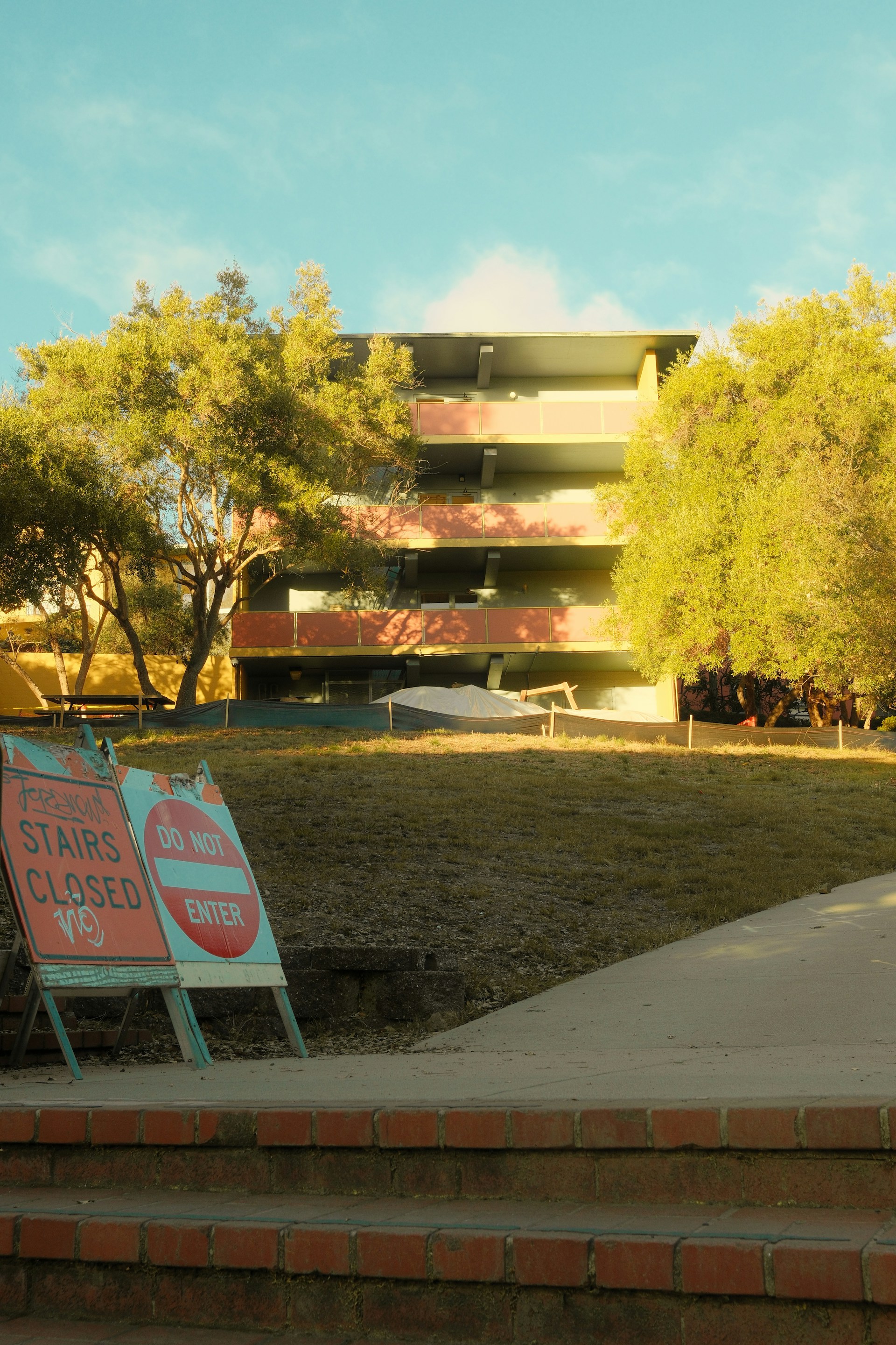 Building with trees and caution signs on grass
