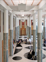 Modern hall with marble columns and geometric floor patterns.