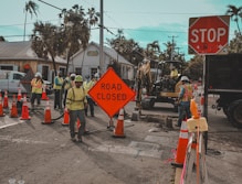 Construction workers and road closed signs on a street.