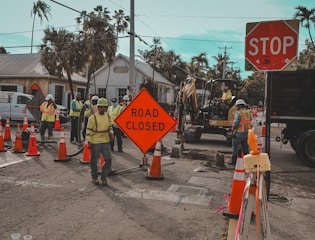 Construction workers and road closed signs on a street.