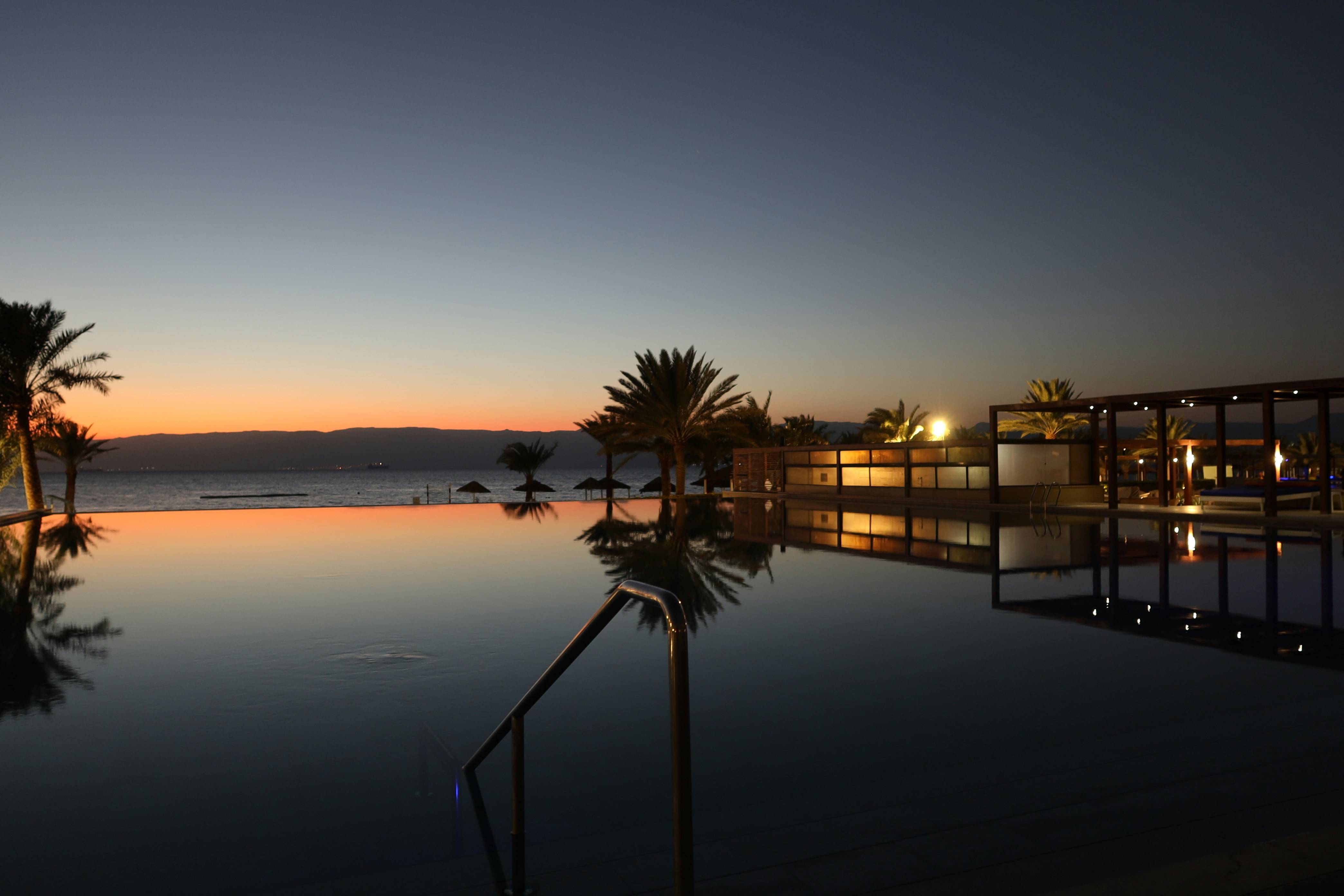 Infinity pool at dusk with palm trees and ocean