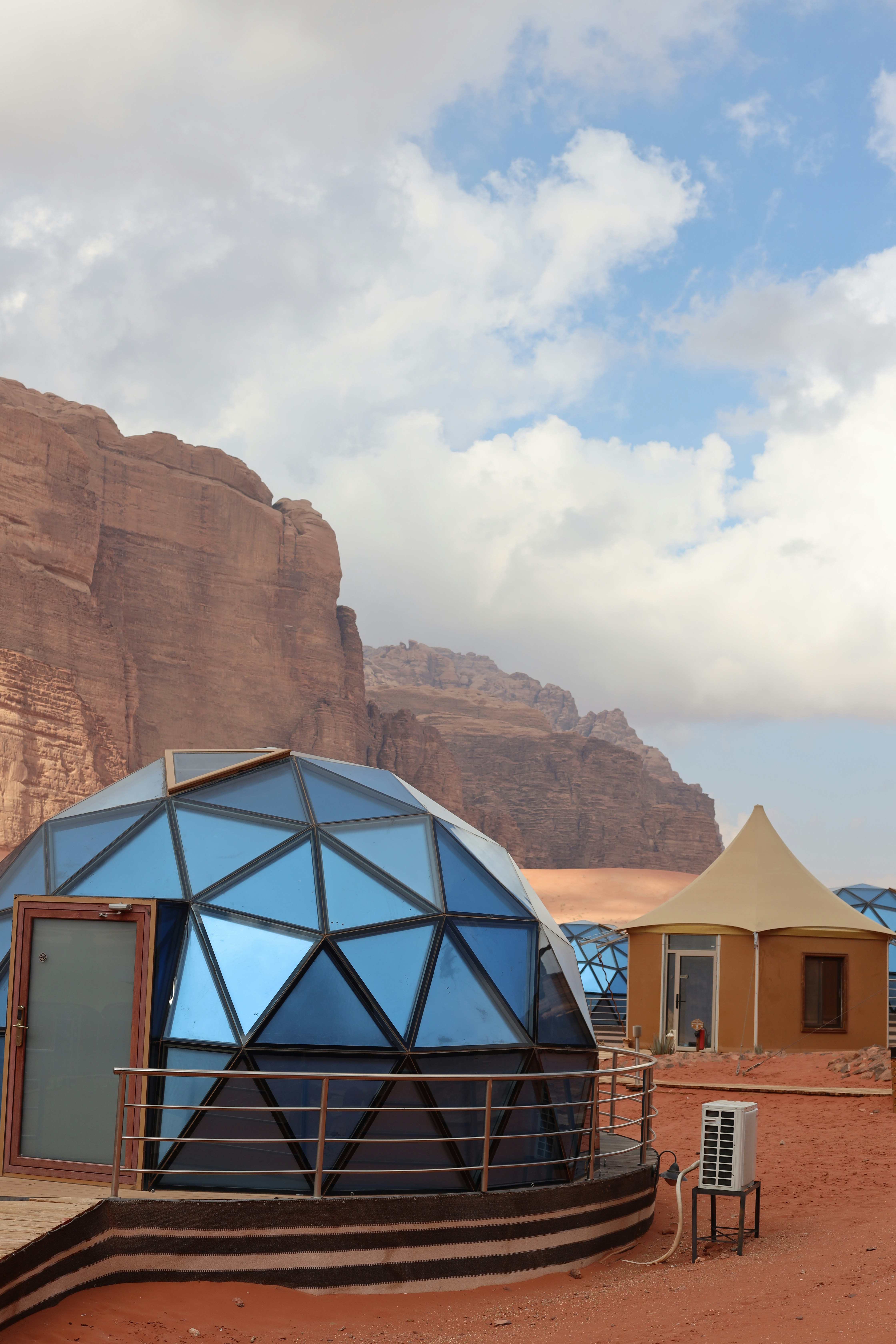 Geodesic dome and tent accommodations in desert landscape.