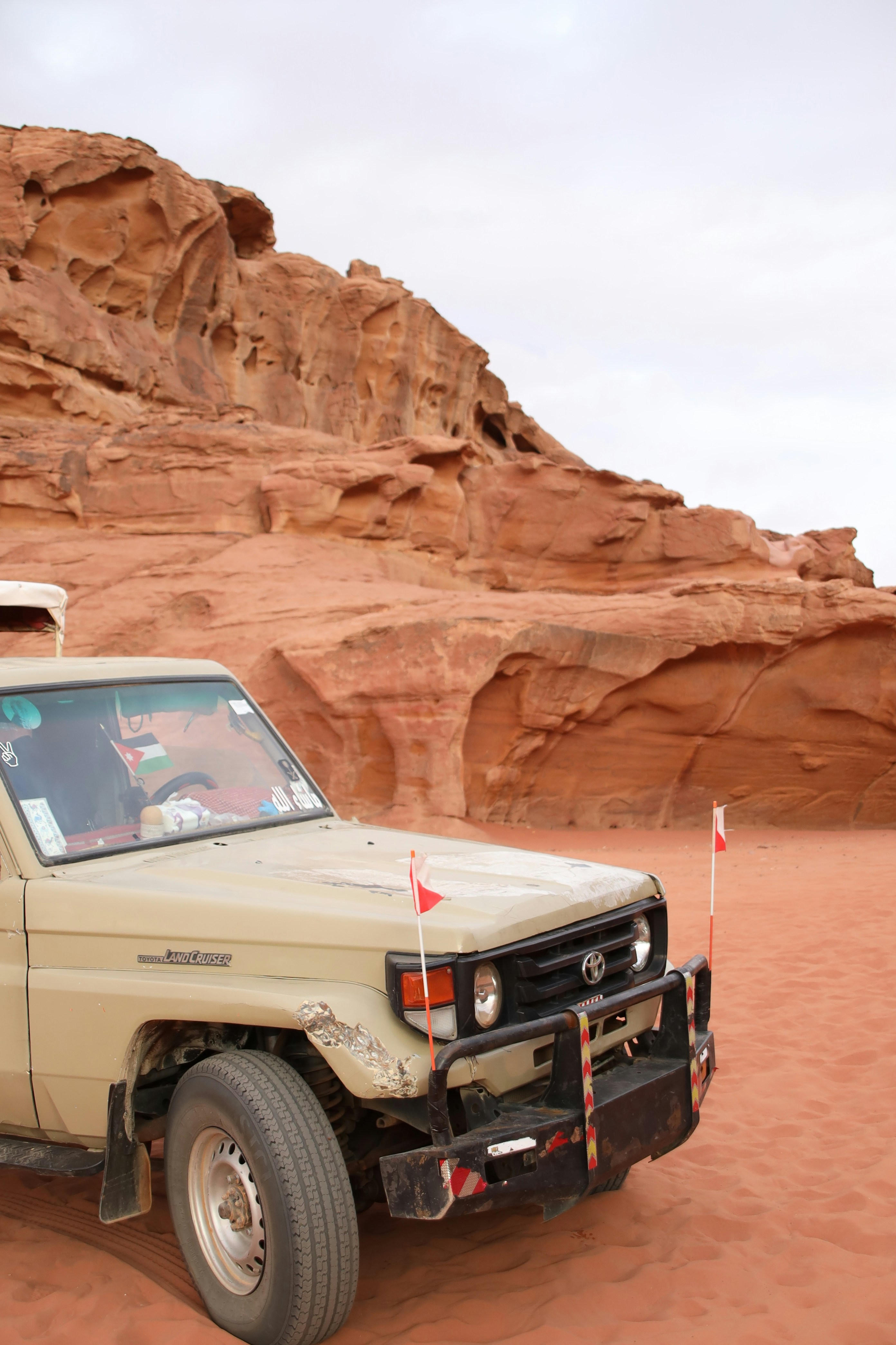 A beige off-road vehicle parked in a desert landscape.