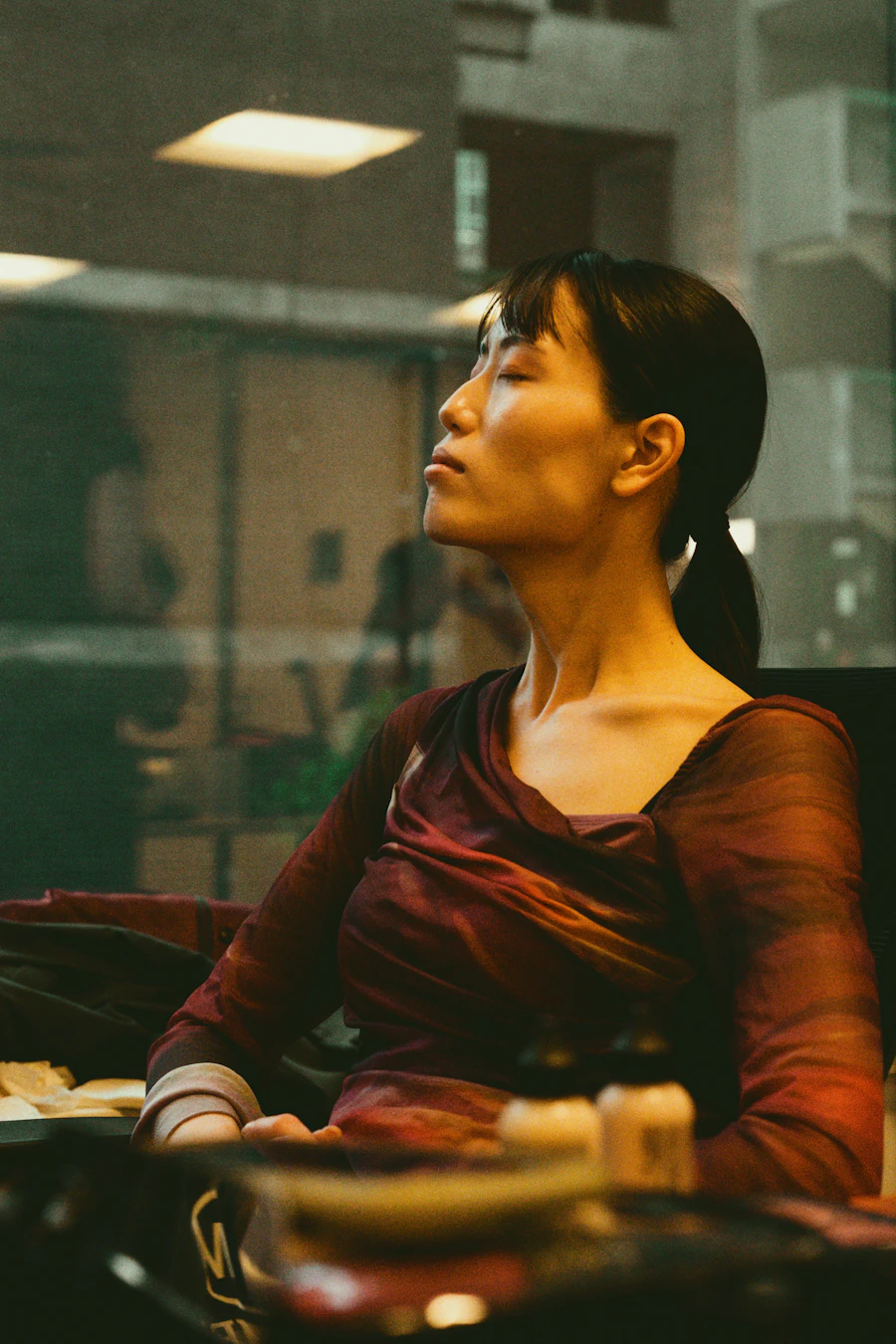 An adult sits with eyes closed, head gently tilted, turned inward in a soft warm-toned moment of self-reflection