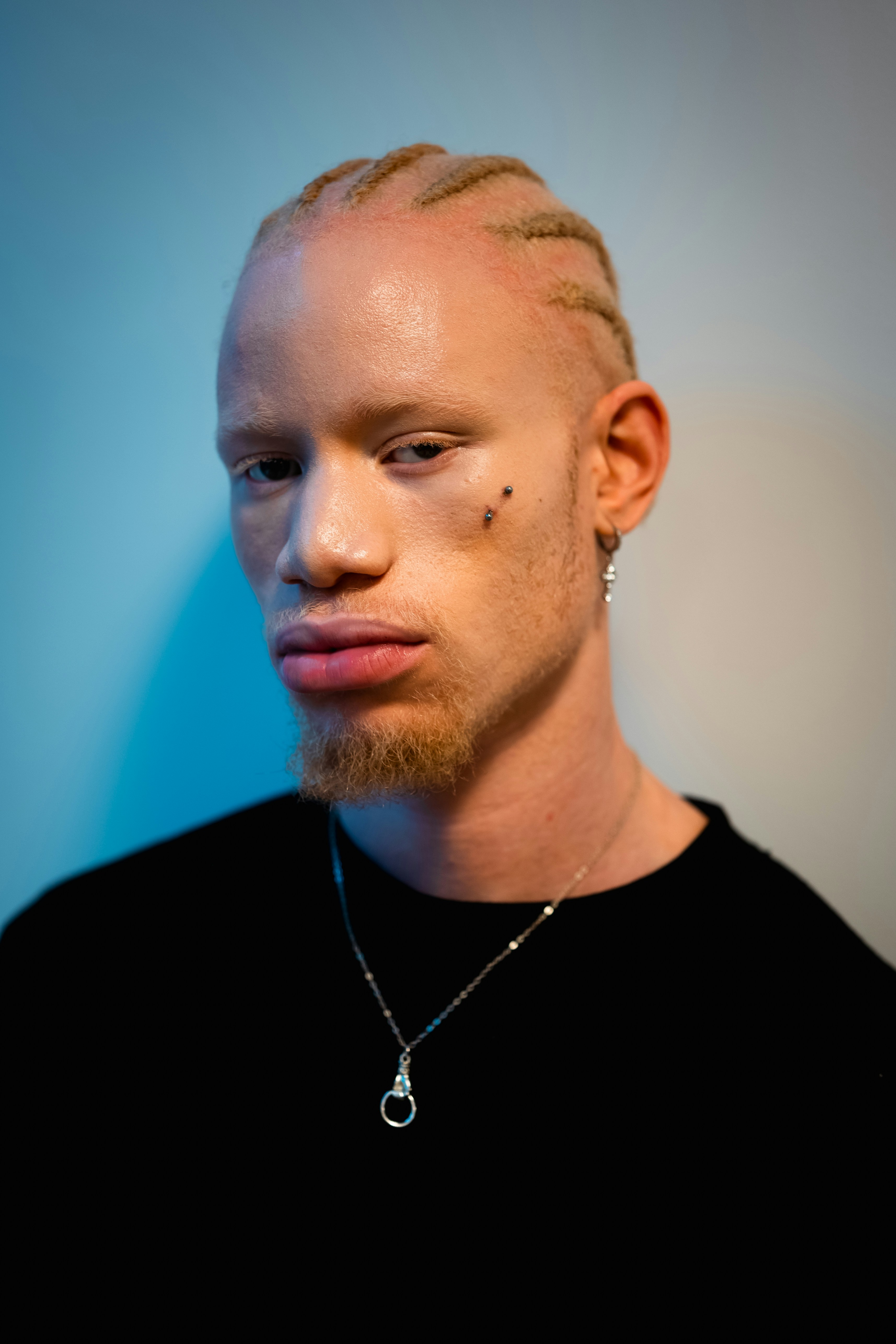 Man with braided hair and beard wearing necklace