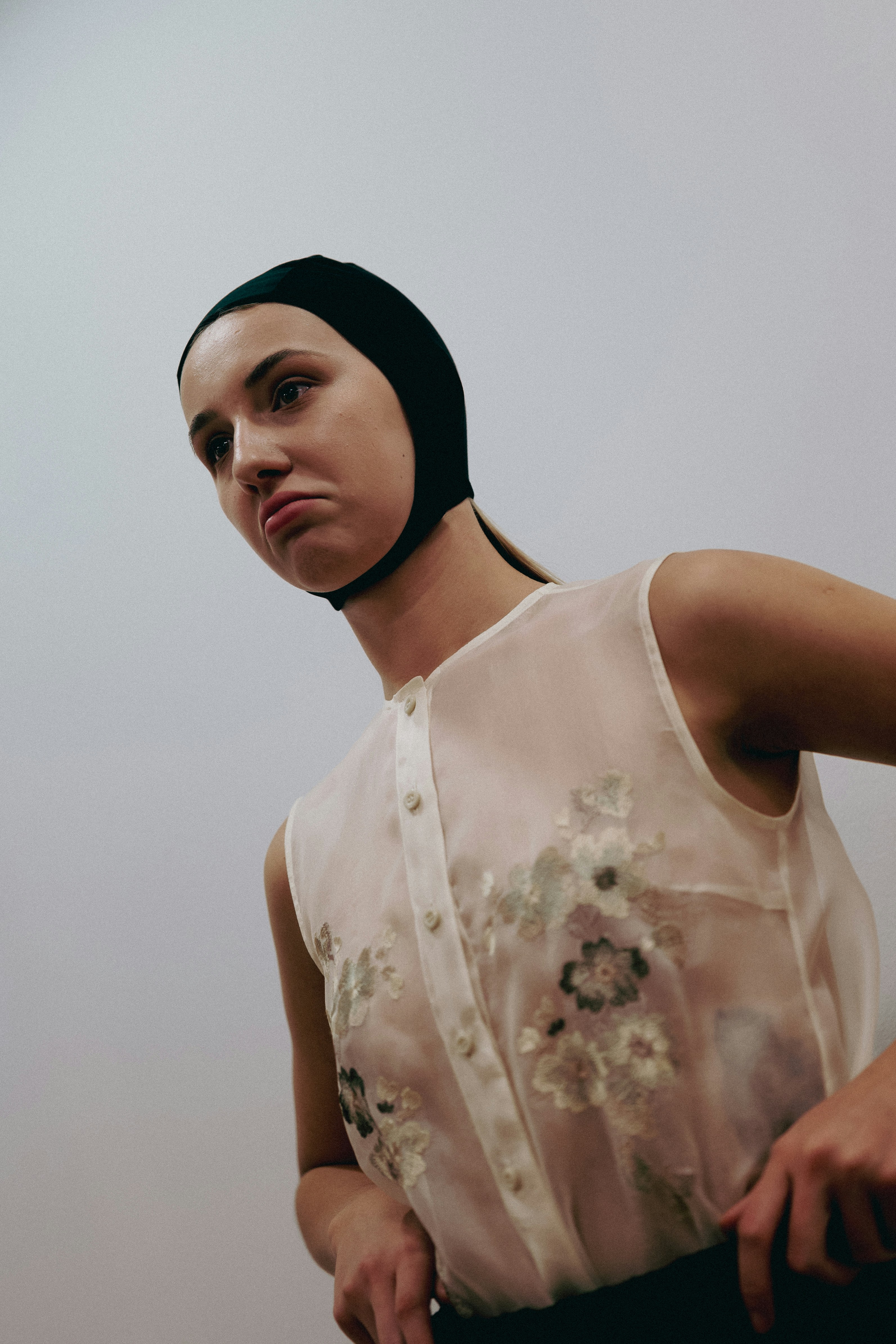 Young woman wearing a black cap and sheer floral blouse