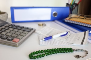 Desk with calculator, papers, and prayer beads.