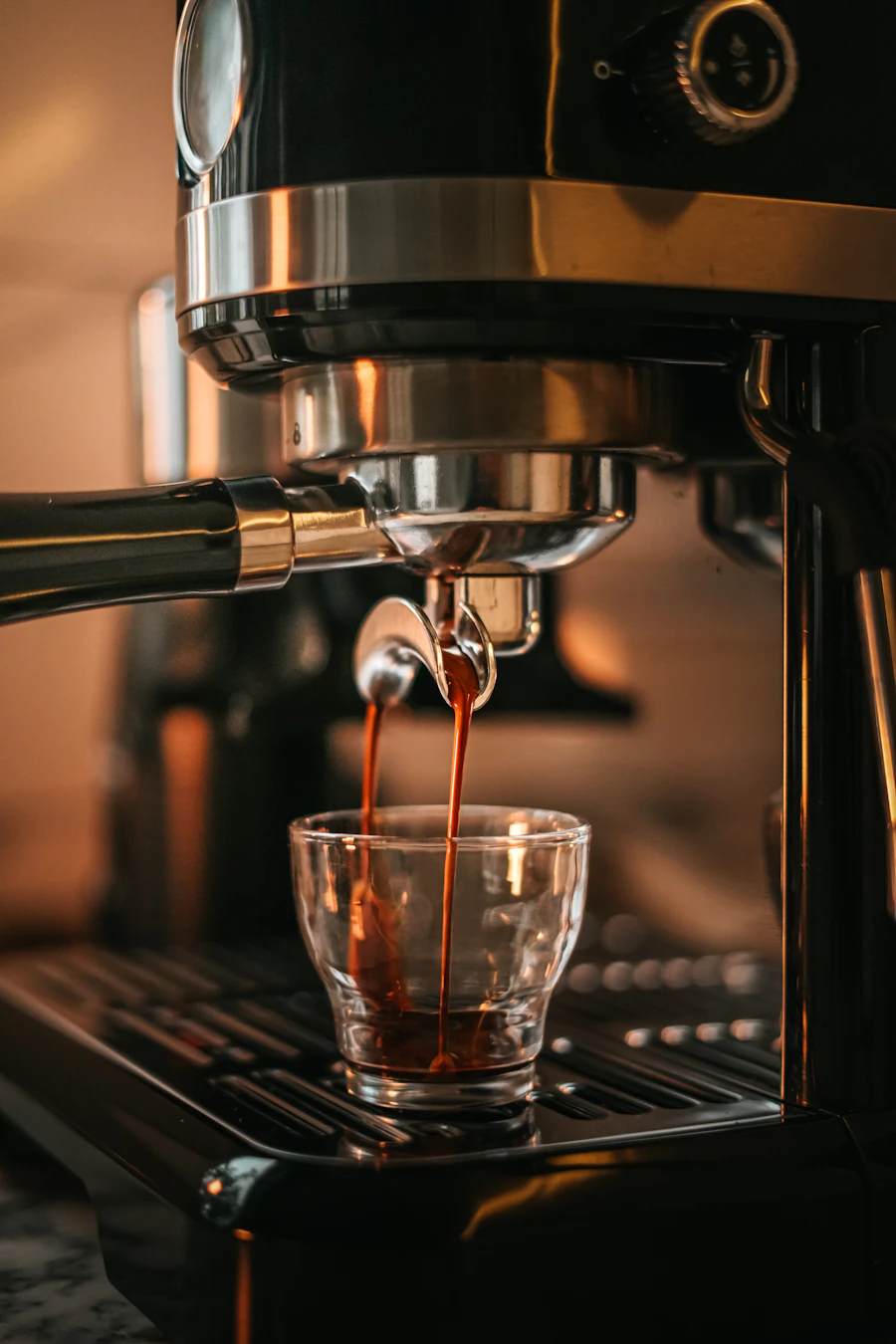 Espresso pouring into a small glass from a polished machine
