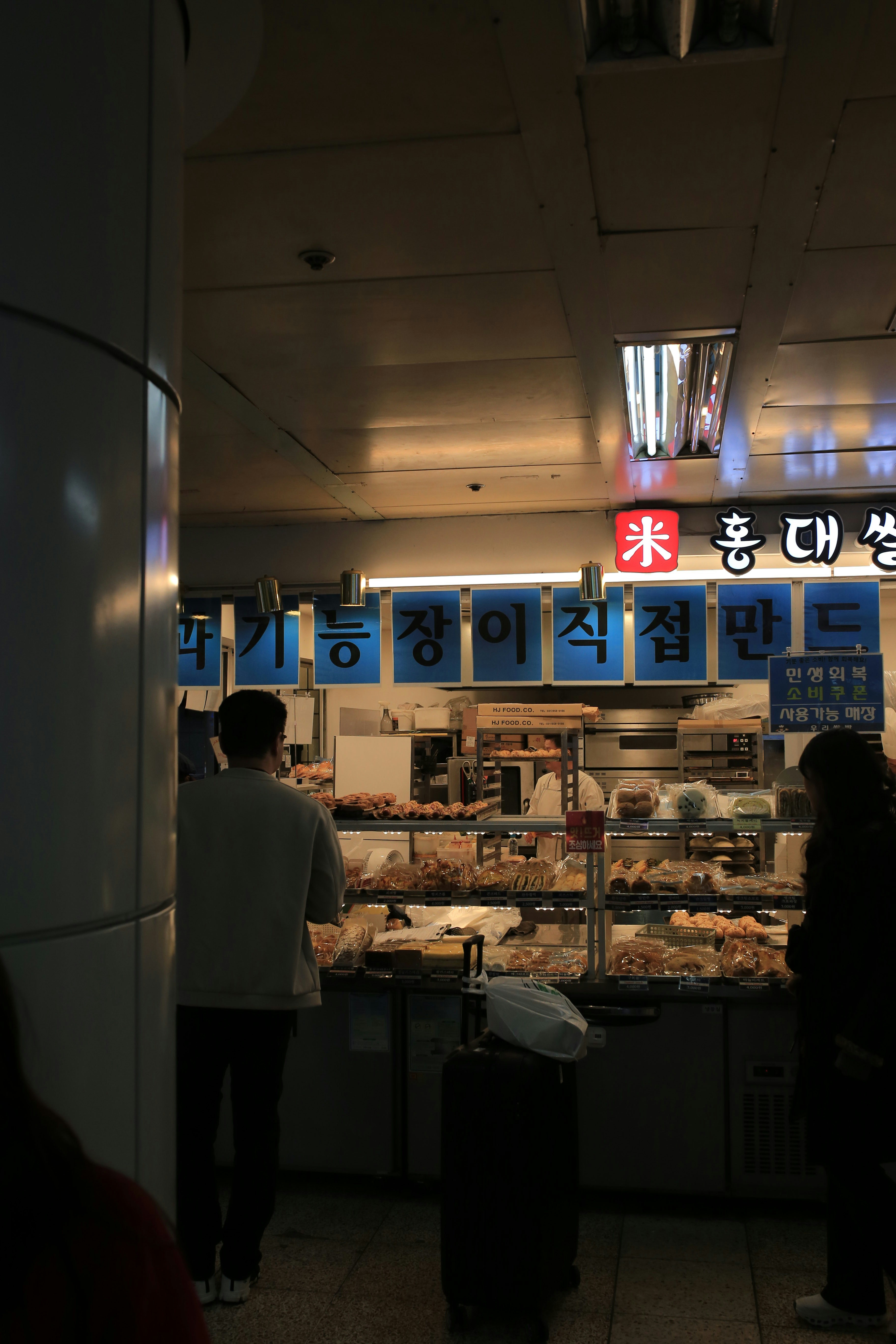 People at a korean bakery with baked goods displayed.