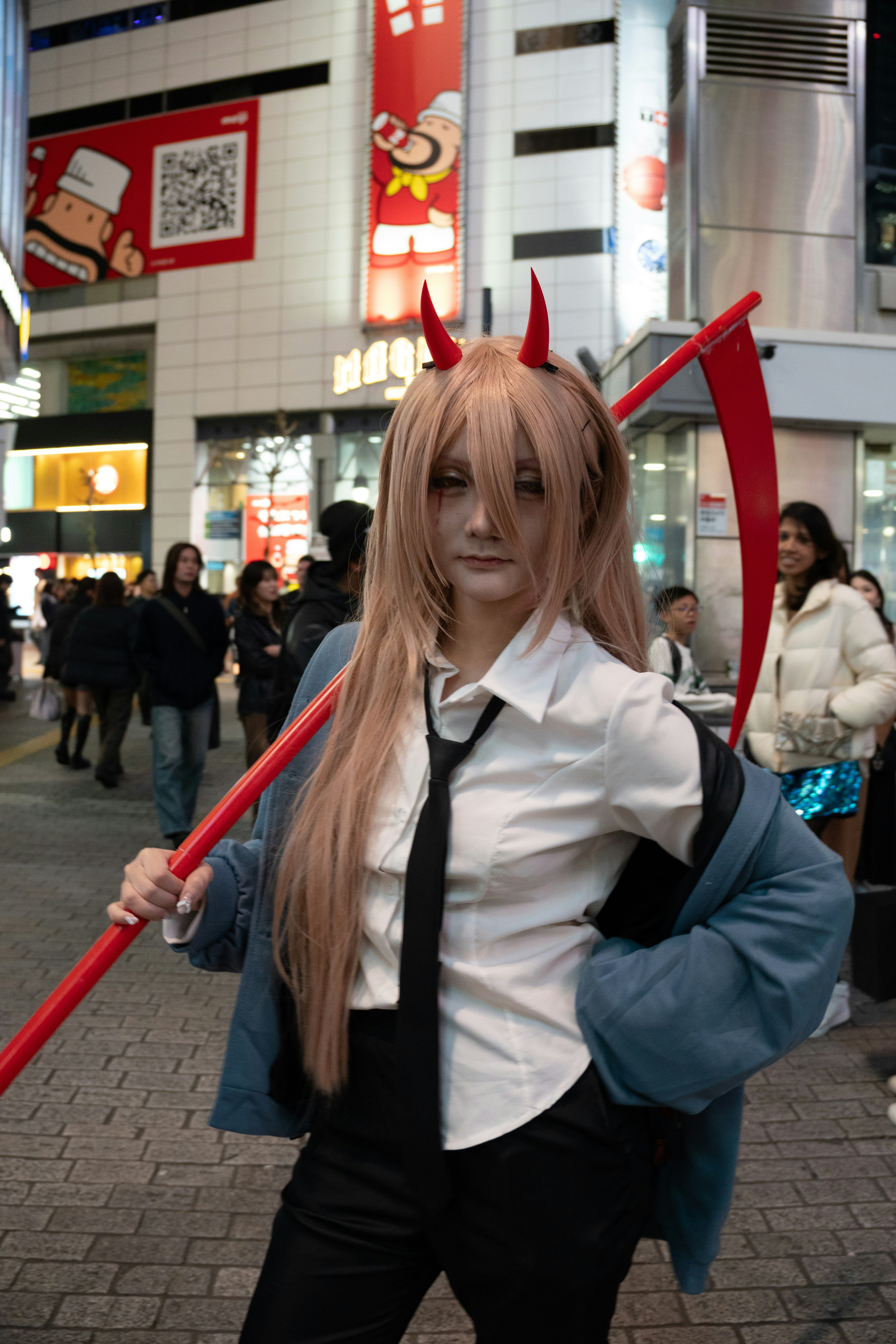 Woman in devil costume with scythe at night
