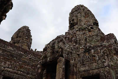 Row of Bayon's giant carved face towers rising above the ruins (via Unsplash)