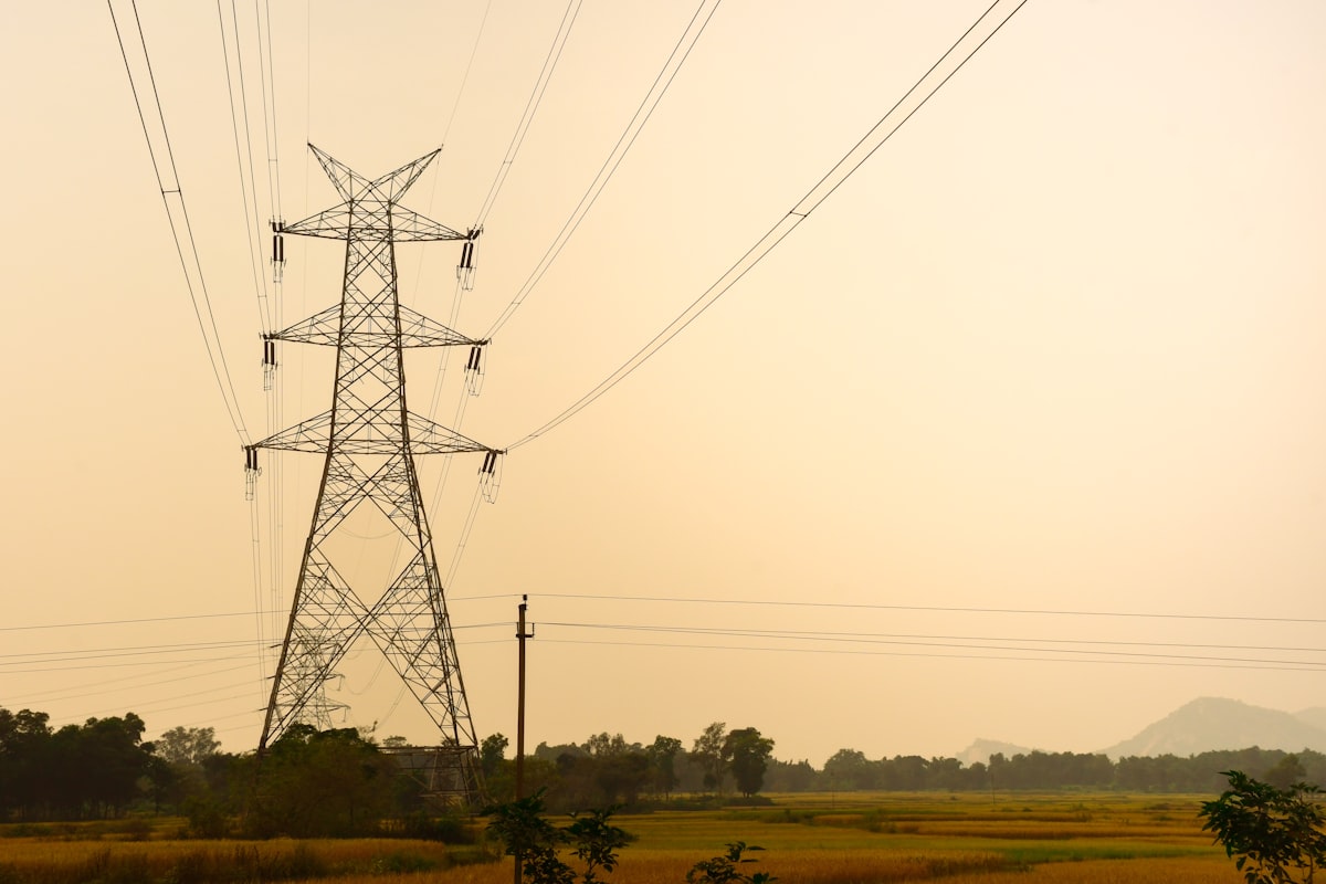 Tall metal pylon with power lines against hazy sky representing electric grid infrastructure