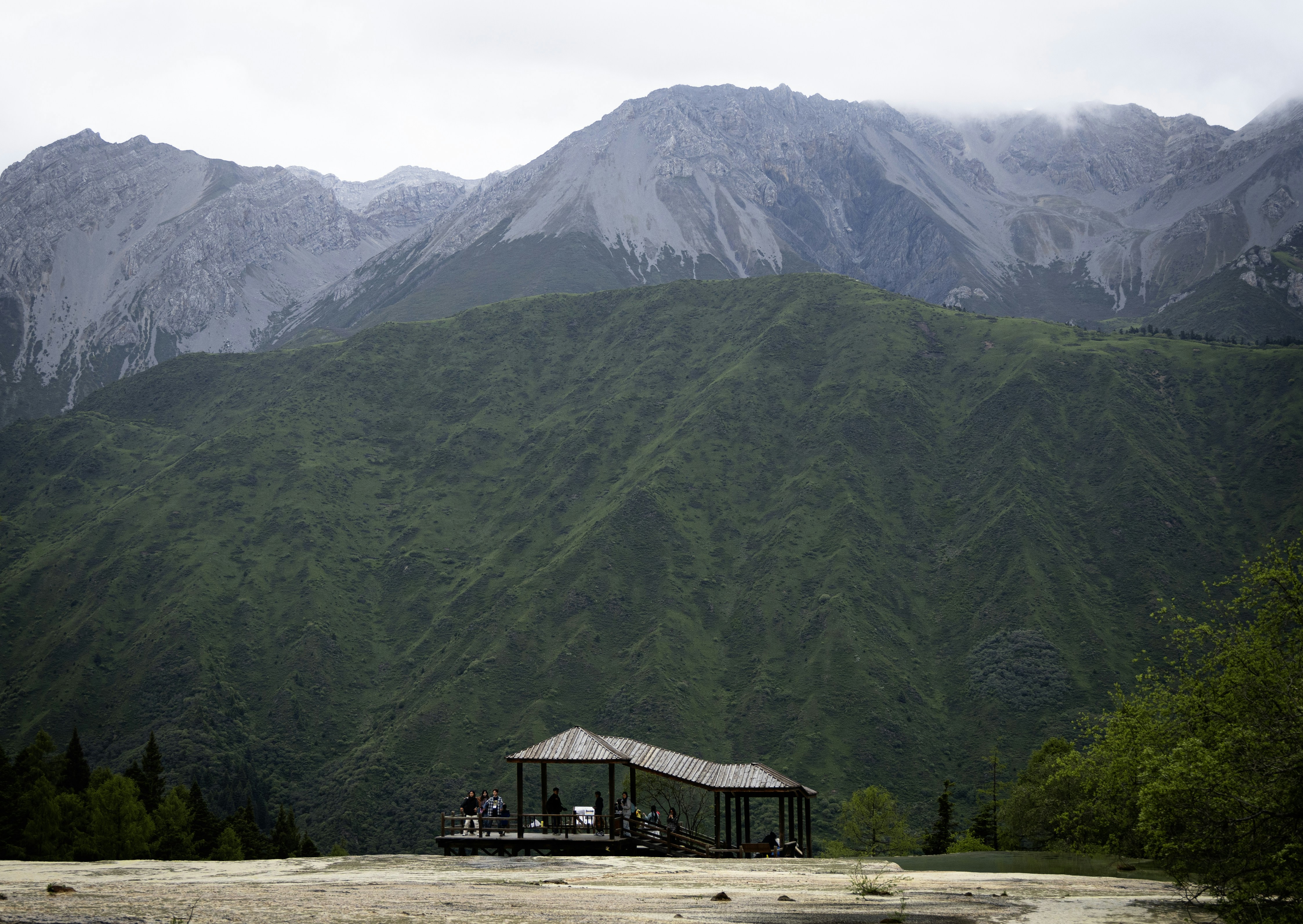 A small building nestled in a lush green mountainous landscape.