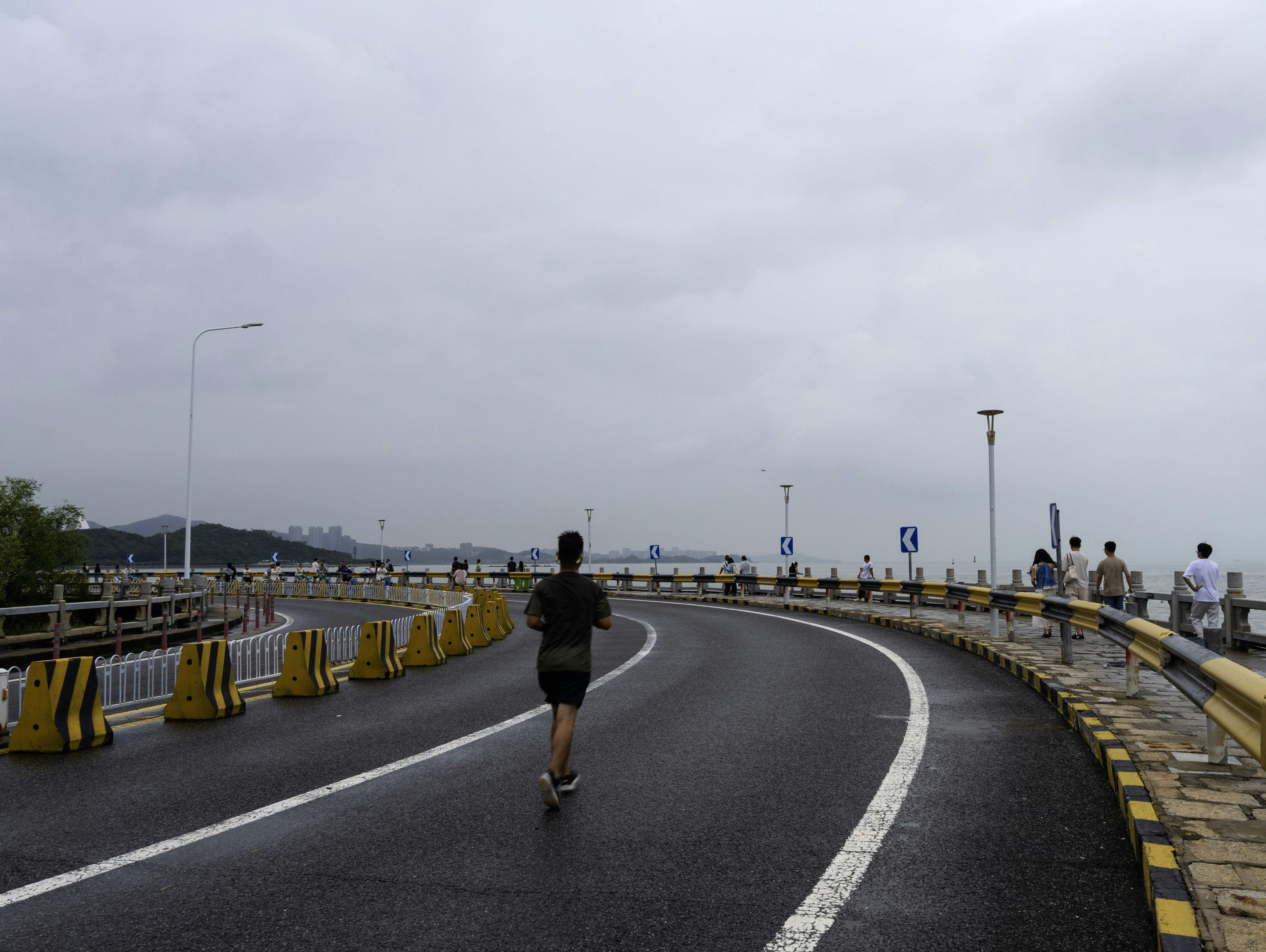 A person running on a road beside the ocean.