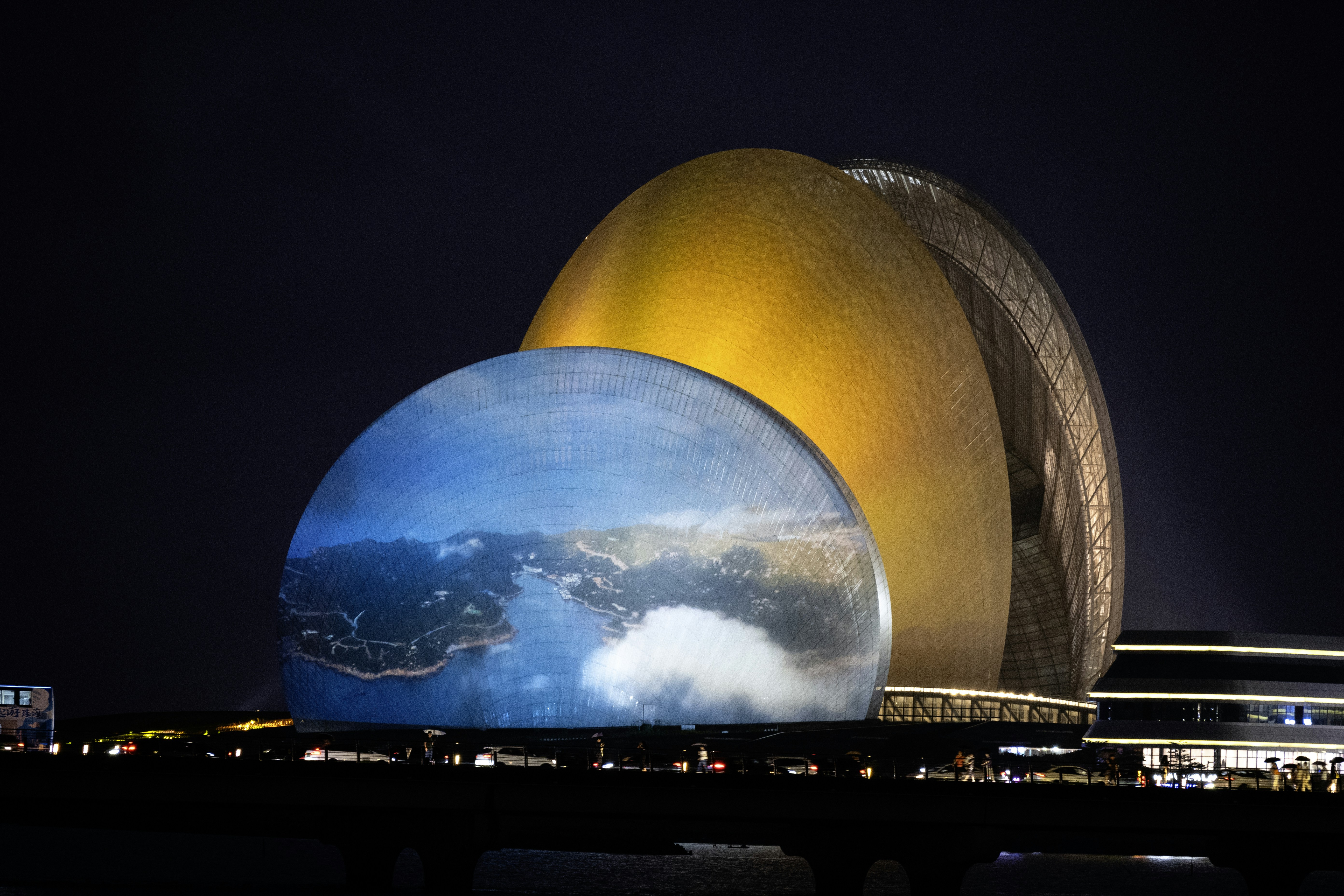 Modern buildings illuminated at night with a globe projection.