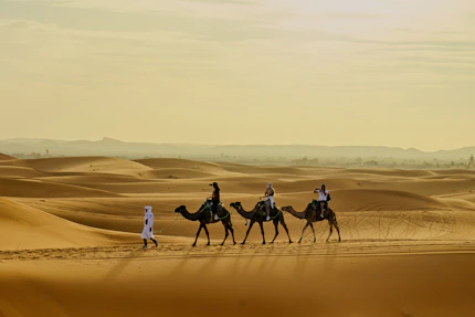 People riding camels through desert sand dunes