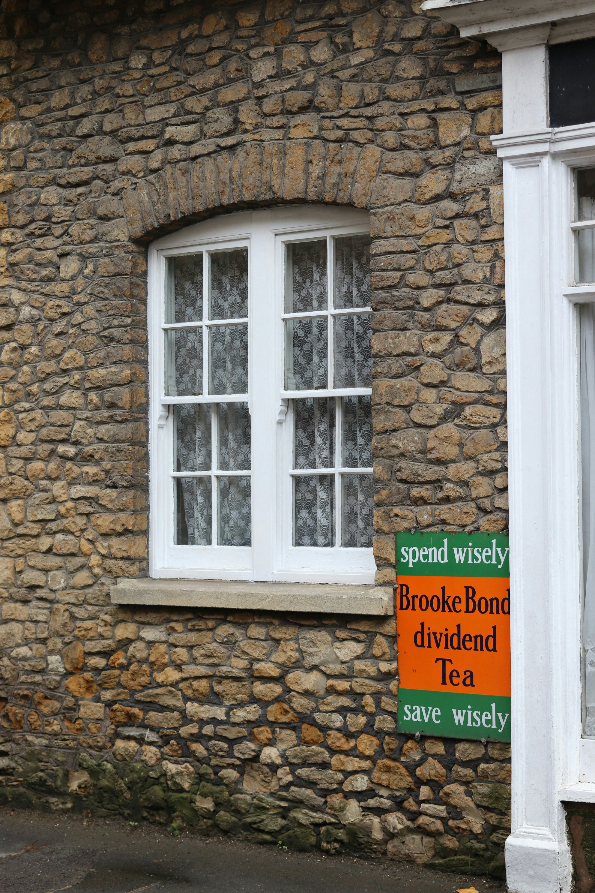 Stone building with a white window and tea advertisement