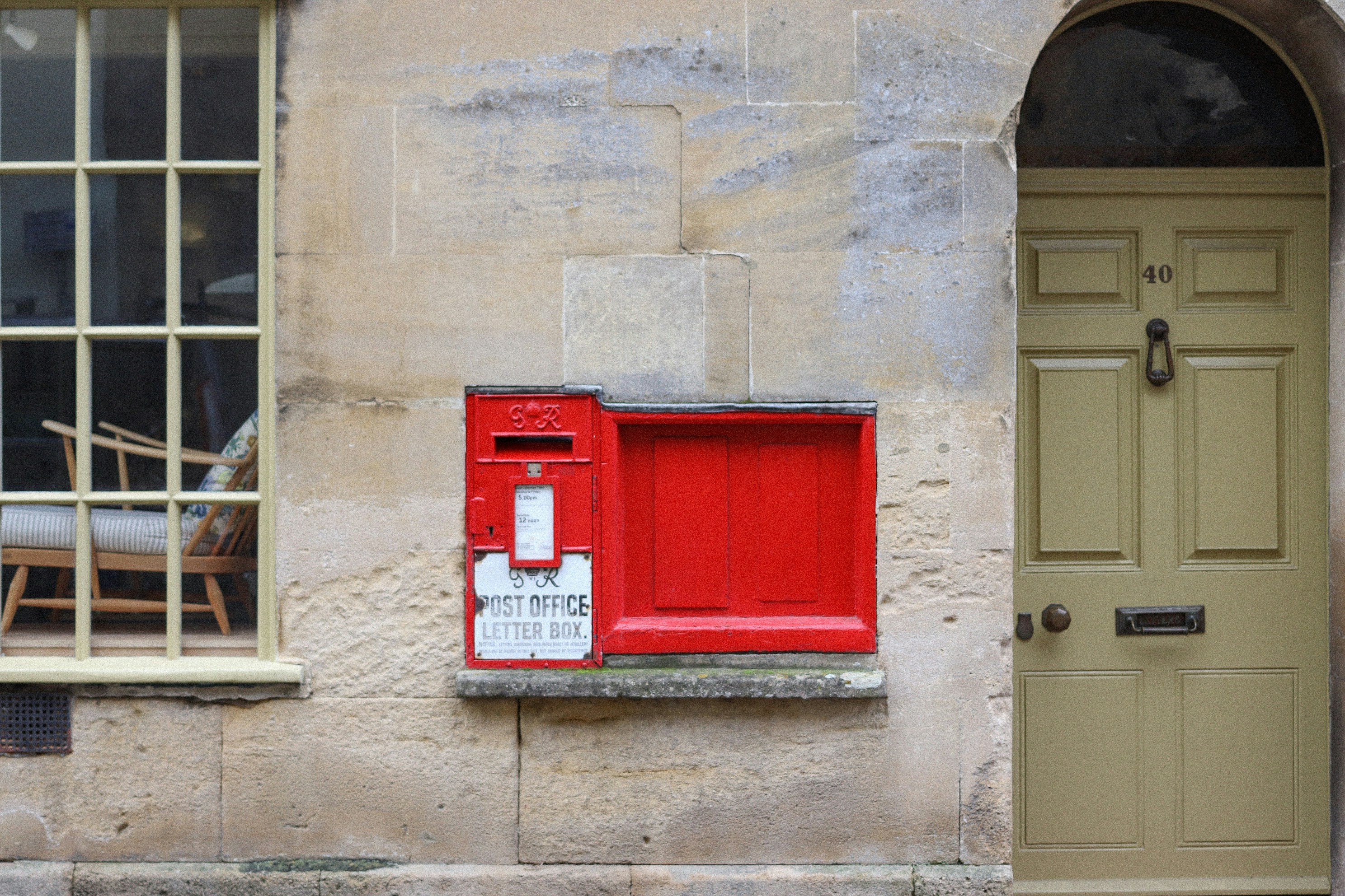 A red post box mounted on a stone wall.