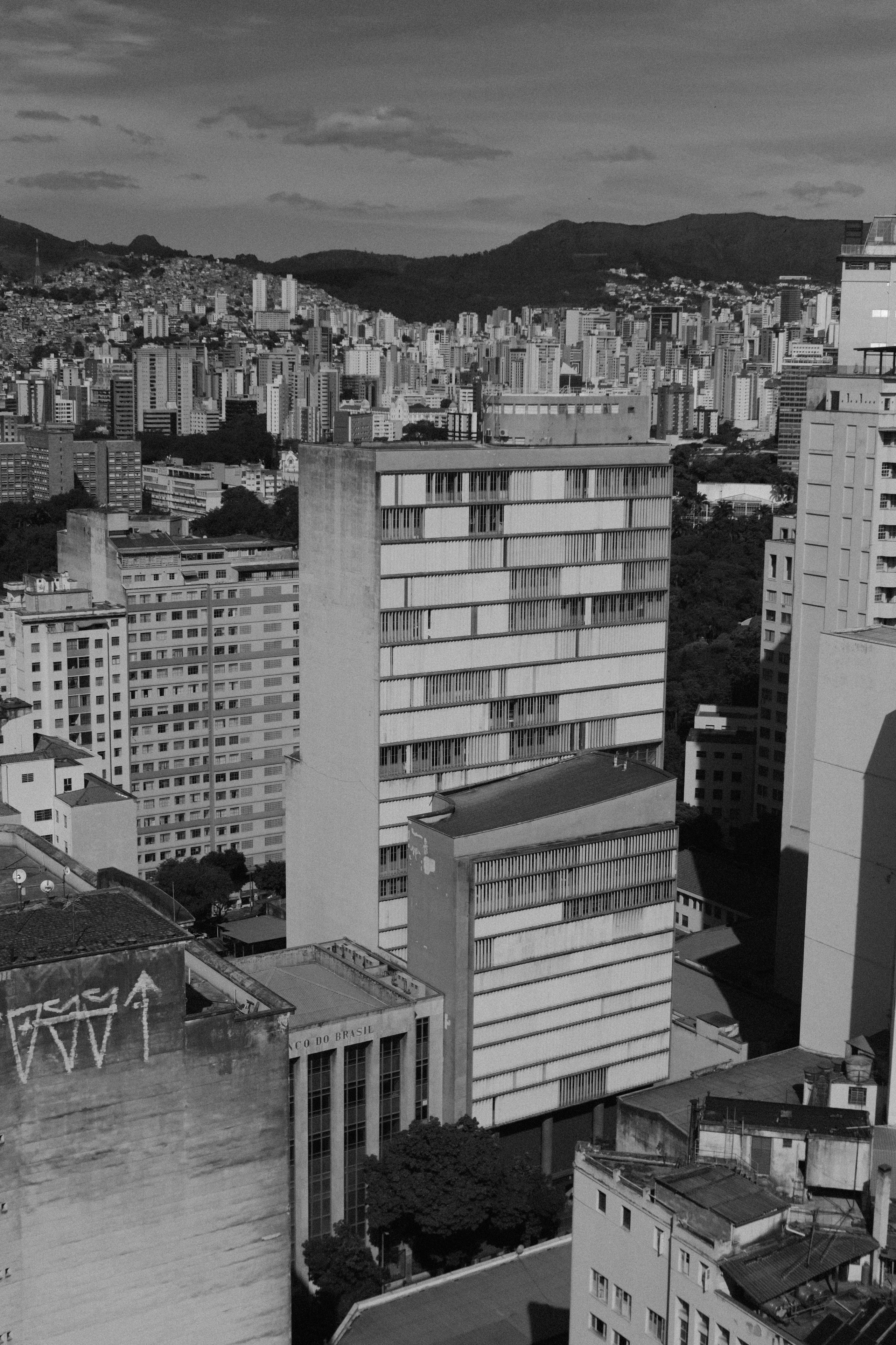 Cityscape with tall buildings and distant mountains.